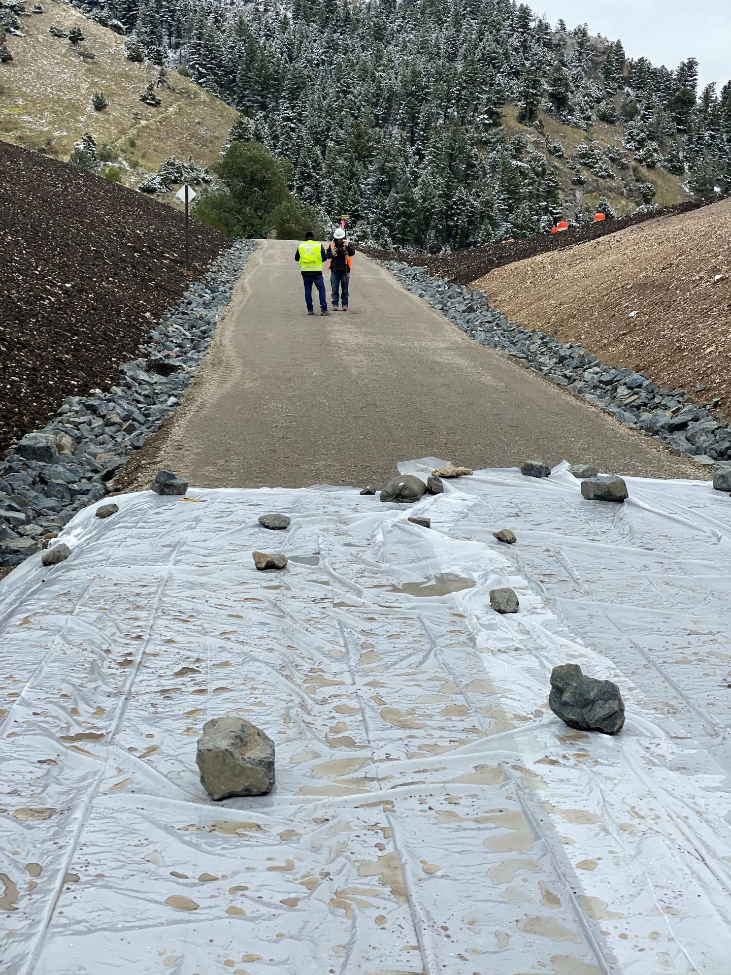 Two men are walking down a road with rocks on the ground.