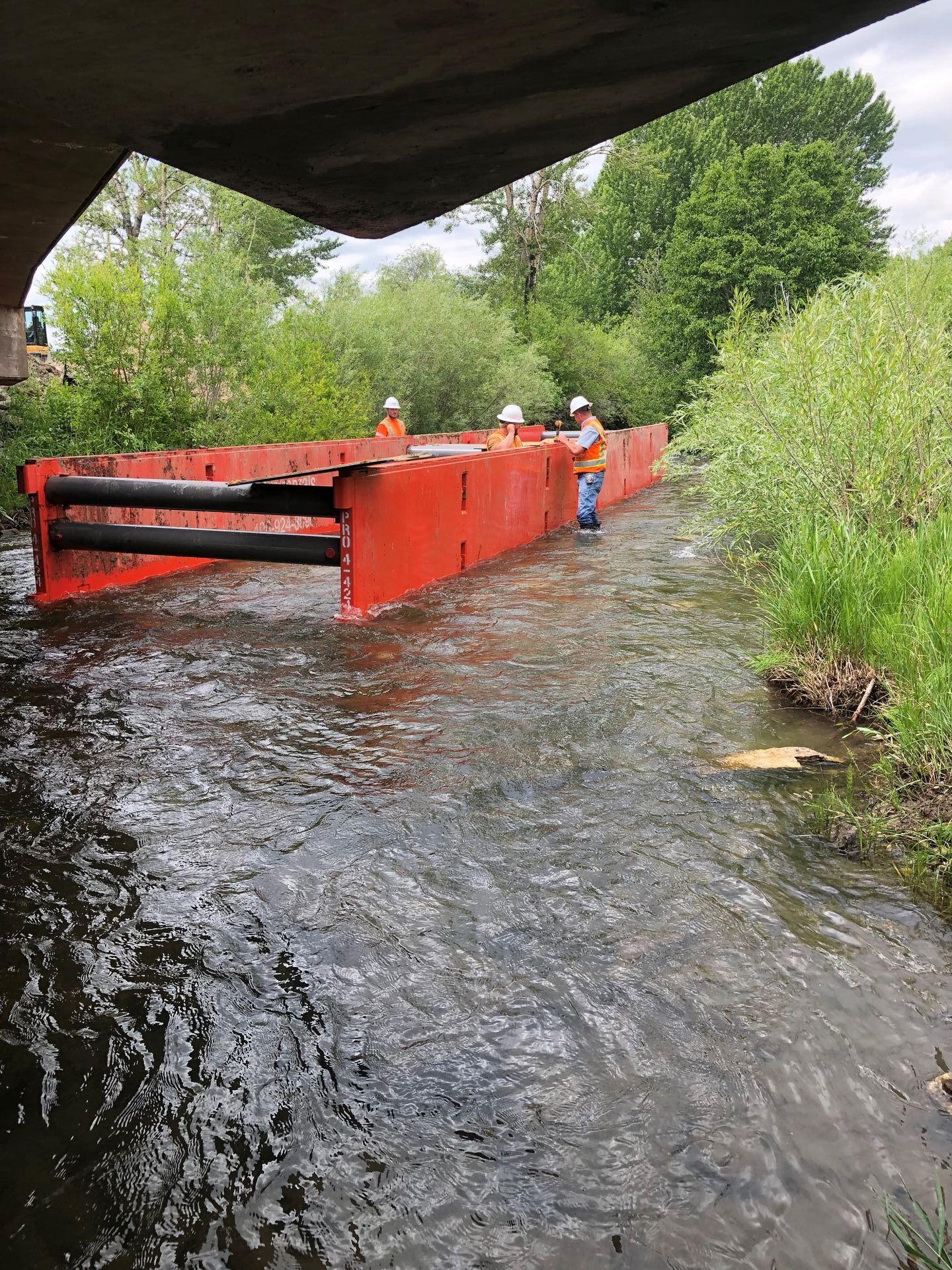 A group of people are working on a bridge over a river.