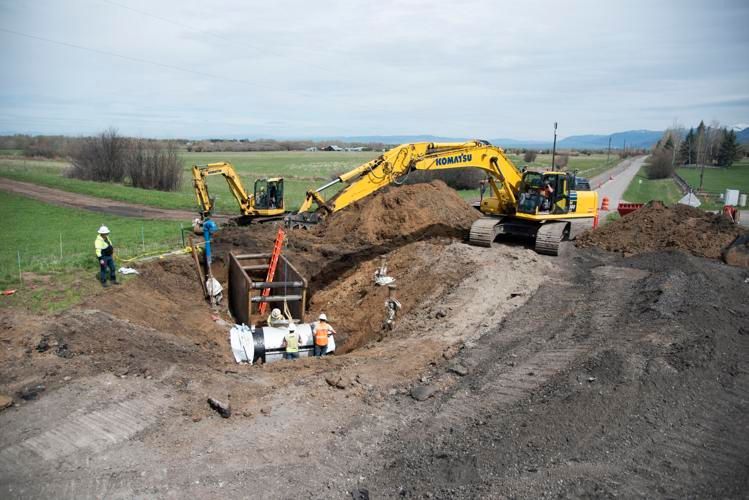 A group of construction workers are digging a trench on the side of a road.