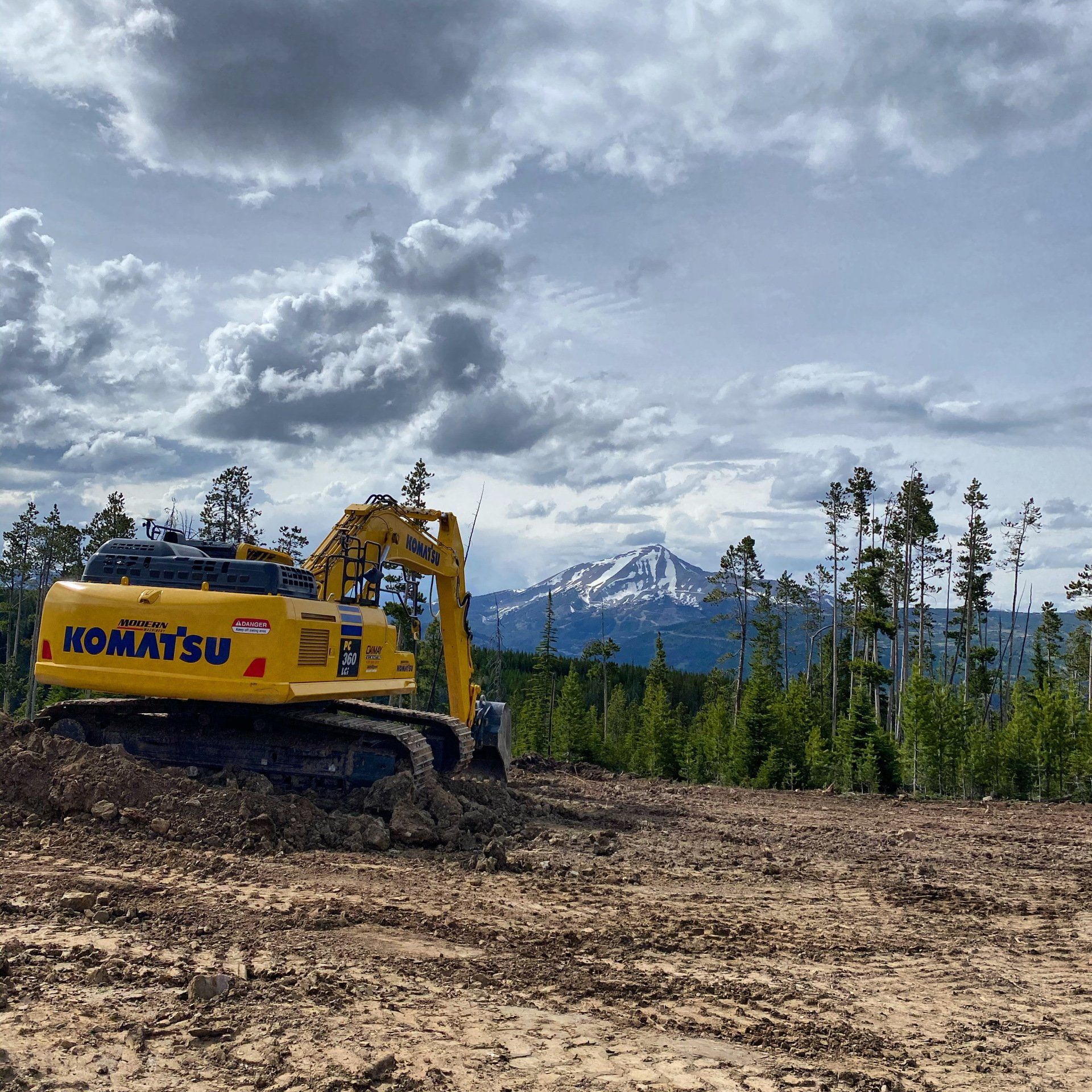 A yellow komatsu excavator is working in a dirt field