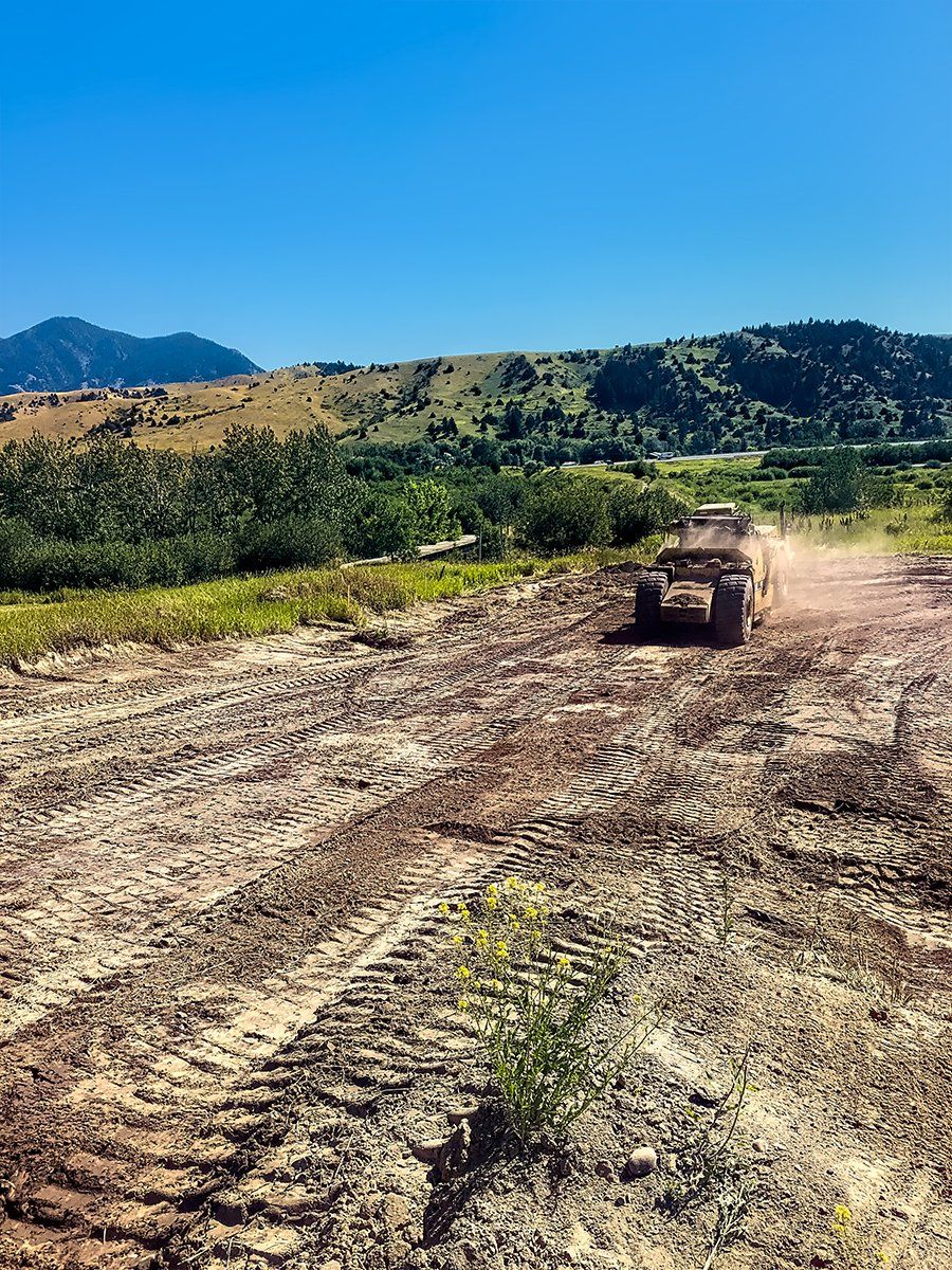 A truck is driving down a dirt road in a field.