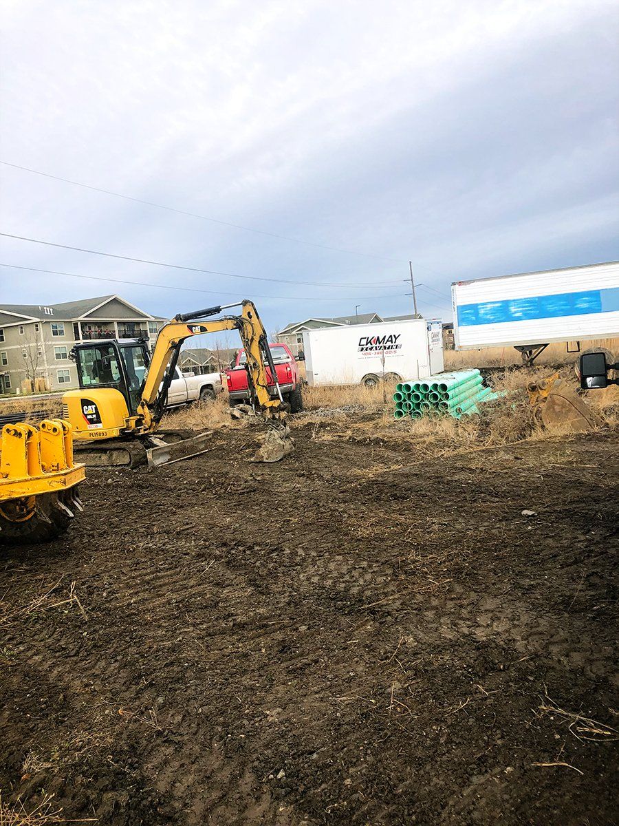 A group of construction vehicles are working on a dirt field.