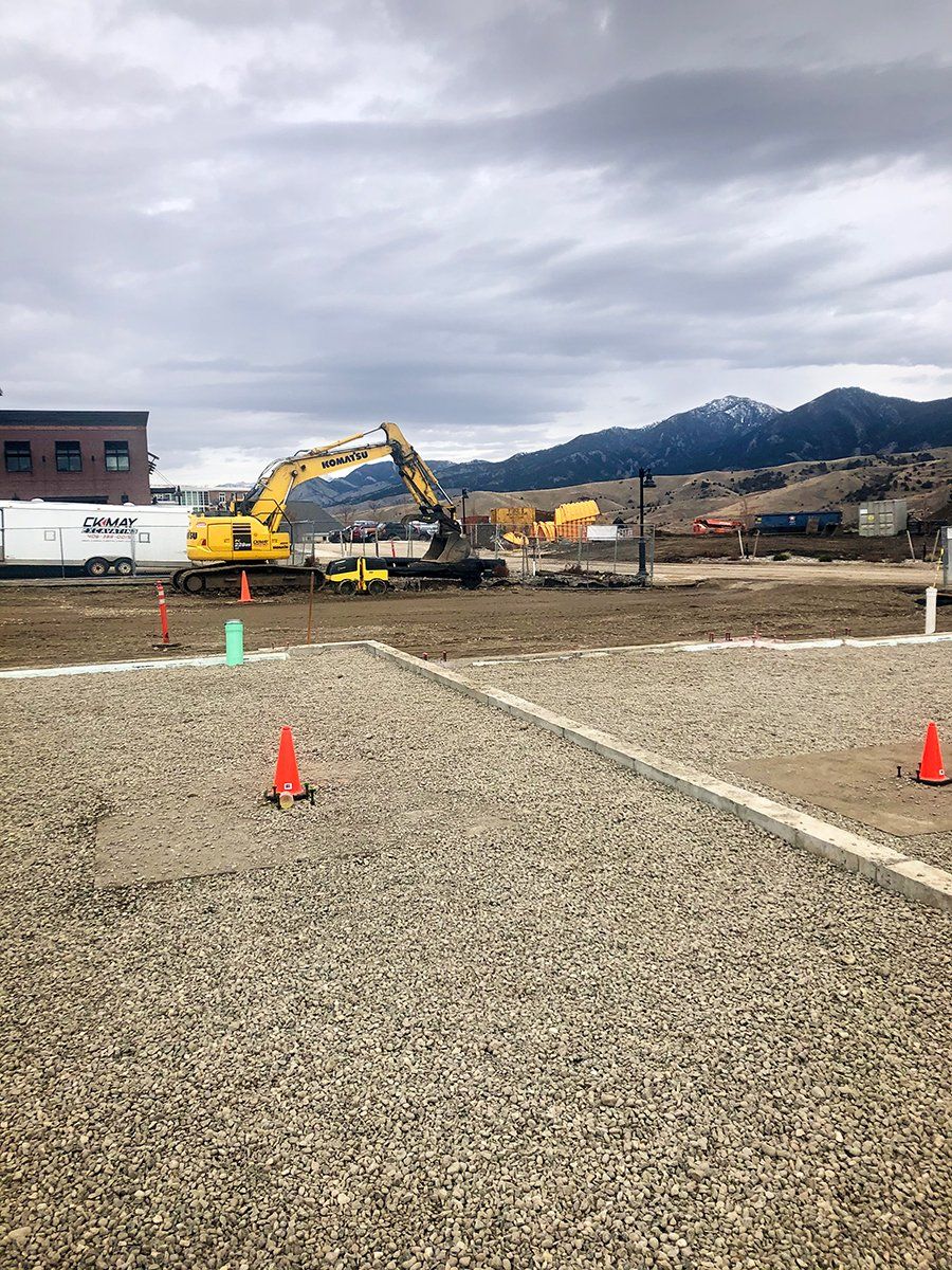 A large yellow excavator is working on a gravel road.