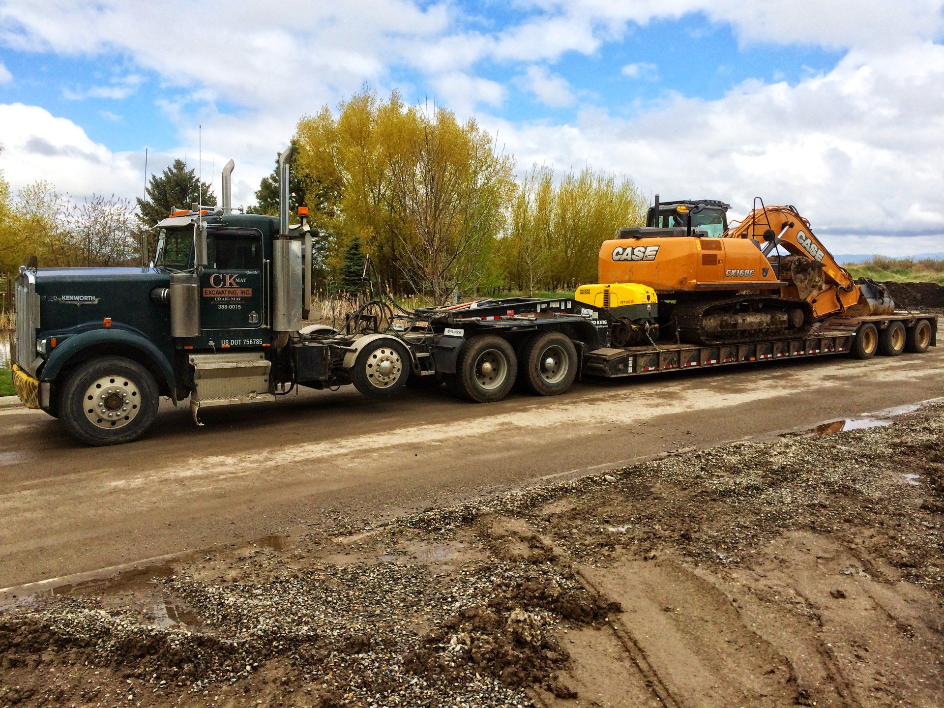 A semi truck is carrying a large excavator on a trailer.