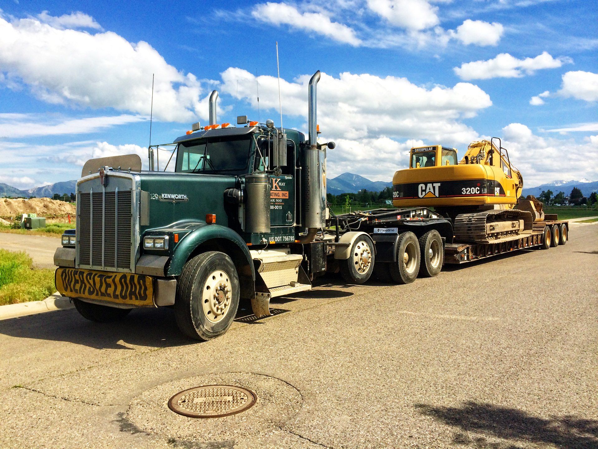 A semi truck is carrying a yellow excavator on a trailer.