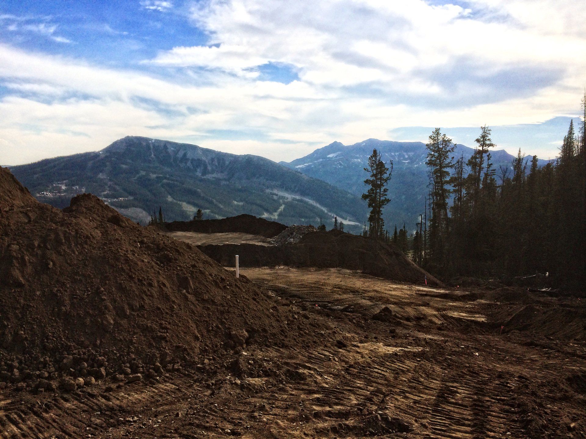 A dirt road with mountains in the background and a pile of dirt in the foreground
