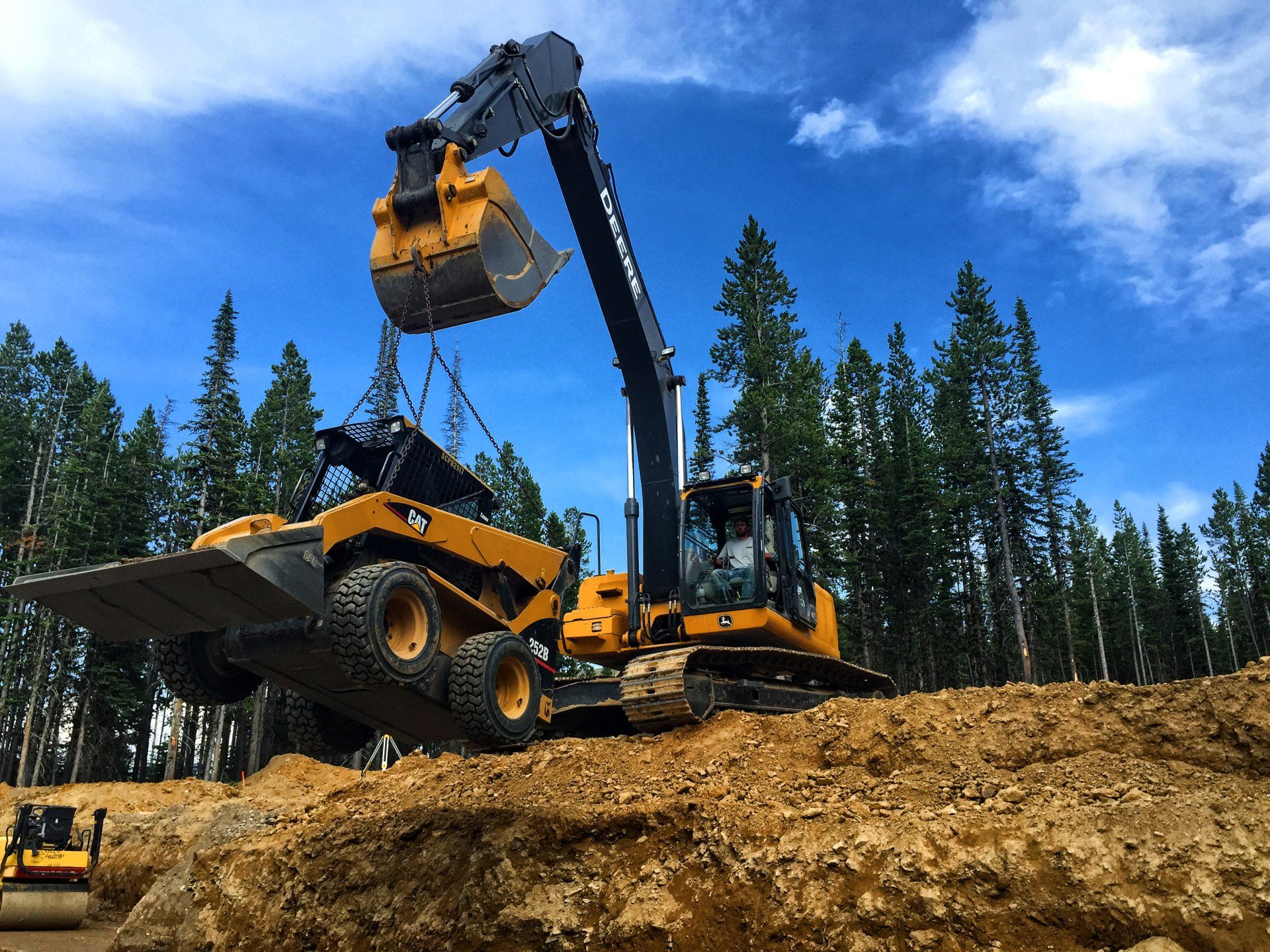 A bulldozer is loading dirt into a dump truck.
