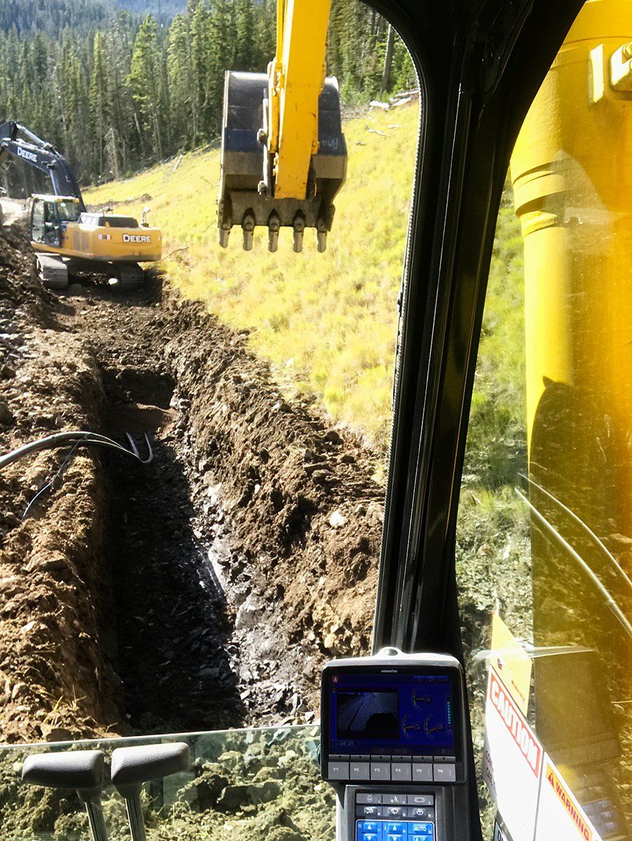 A yellow excavator is digging a hole in the ground