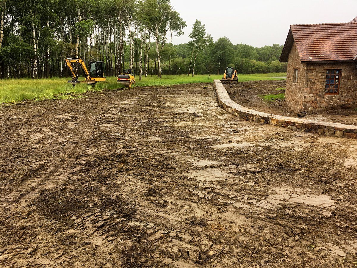 A muddy field with a house in the background and a tractor in the foreground.