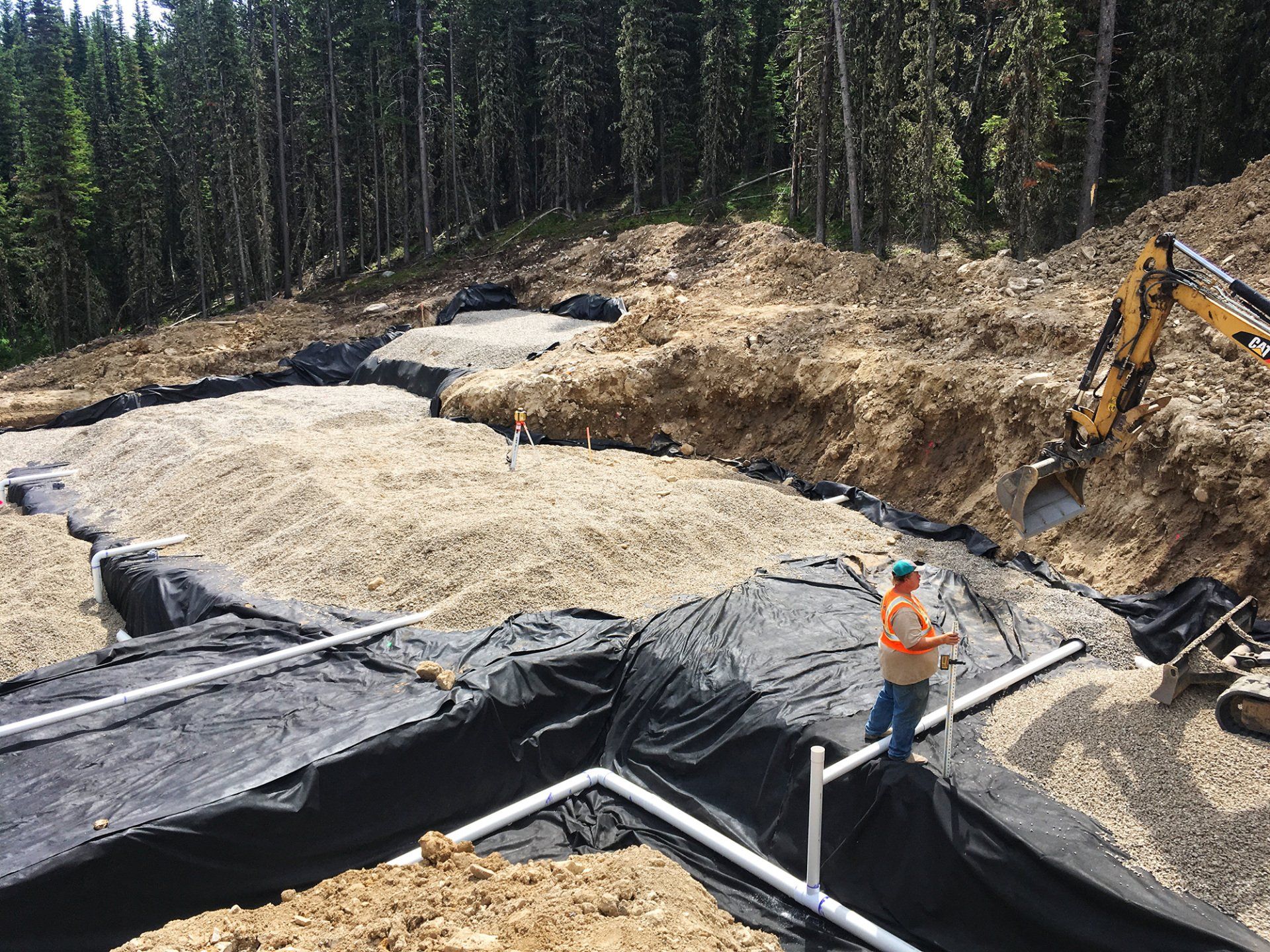 A man is standing in the middle of a dirt field.