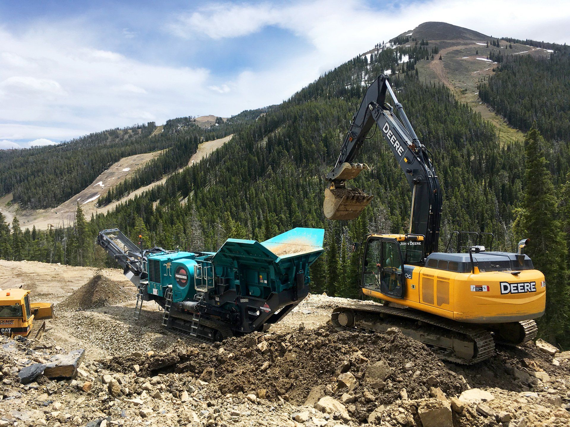 A large excavator is digging a hole in the dirt in the mountains.