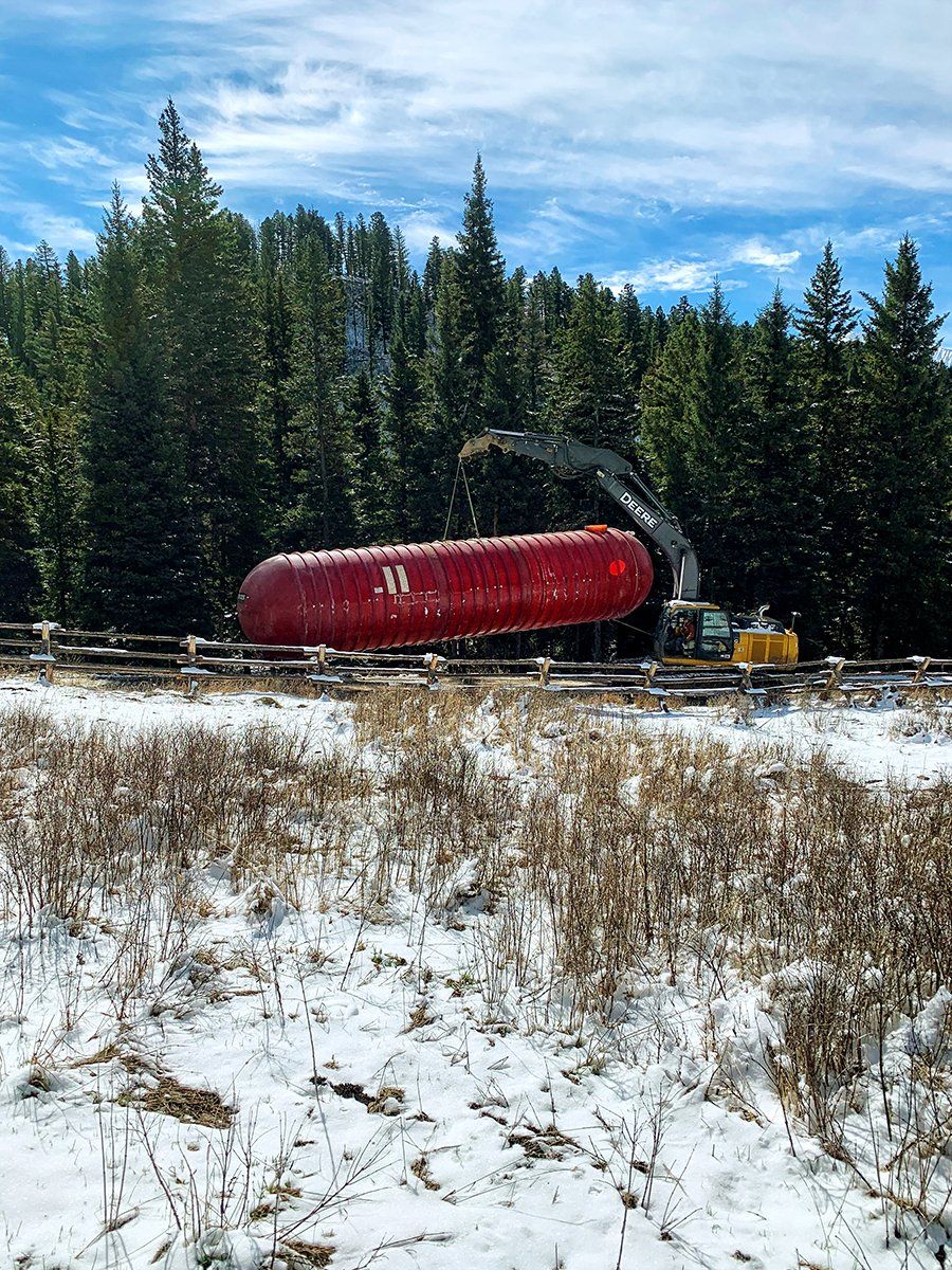 A large red tank is sitting in the middle of a snowy field.
