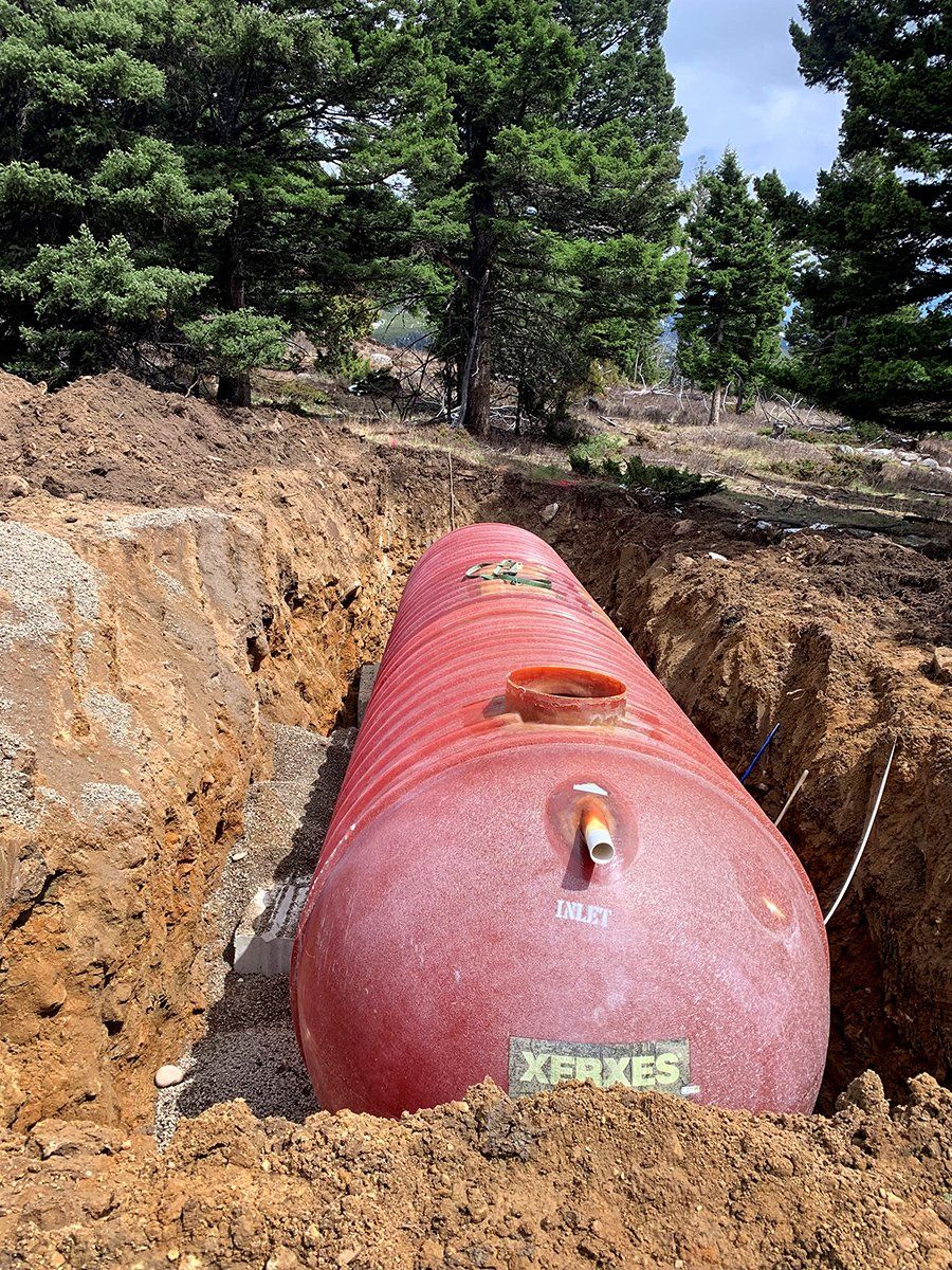 A large red tank is sitting in the middle of a dirt field.