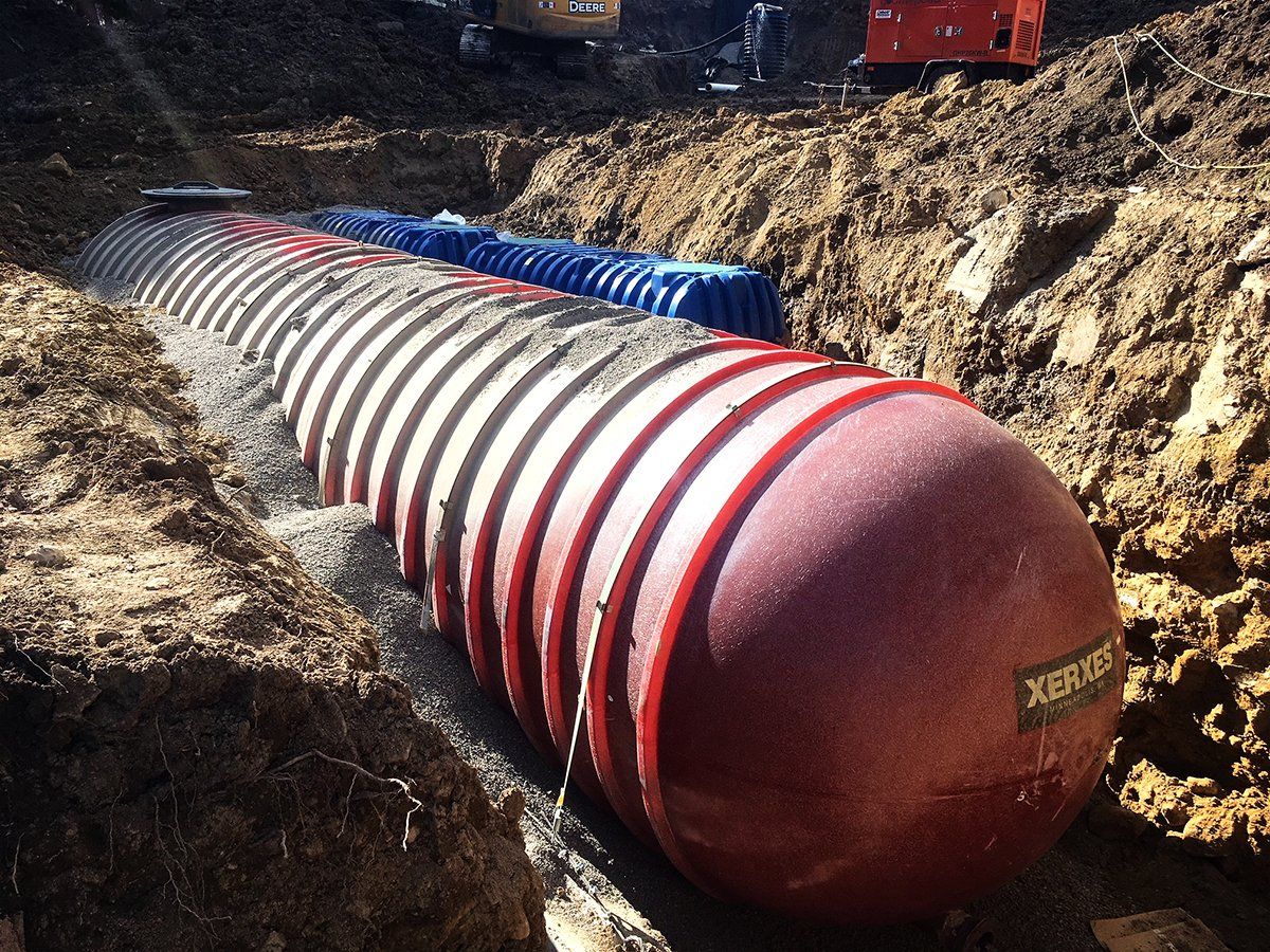 A large red and white pipe is sitting in the dirt.