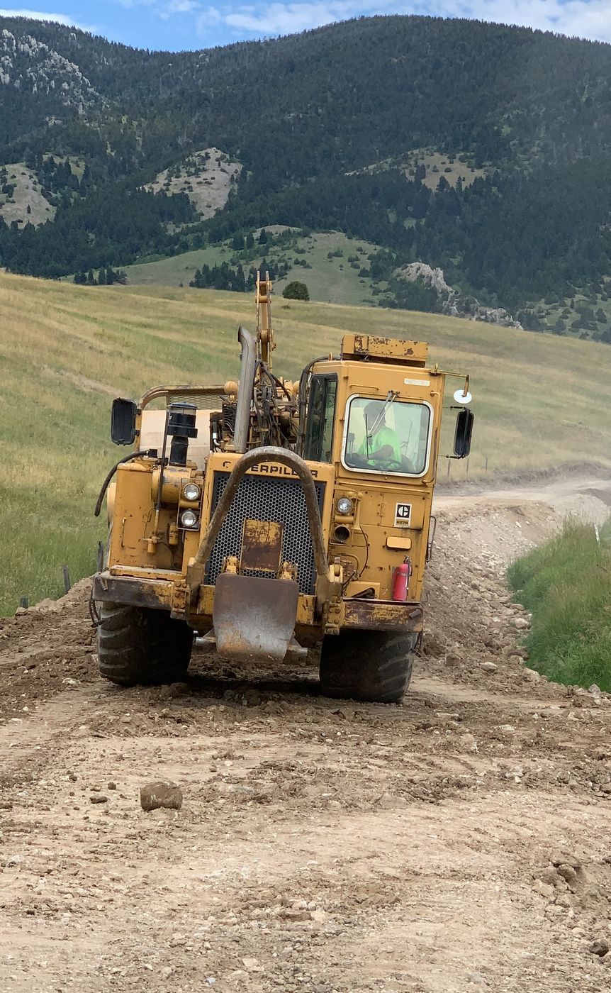 A bulldozer is driving down a dirt road.