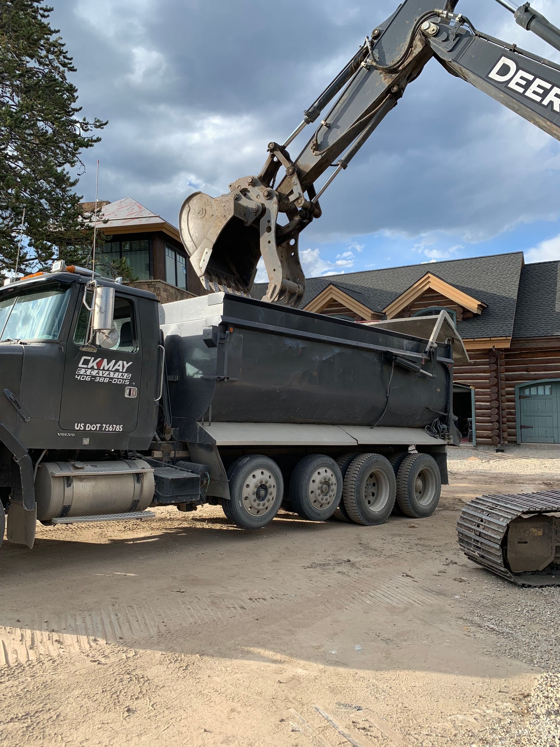 A dump truck is being loaded with dirt by an excavator.