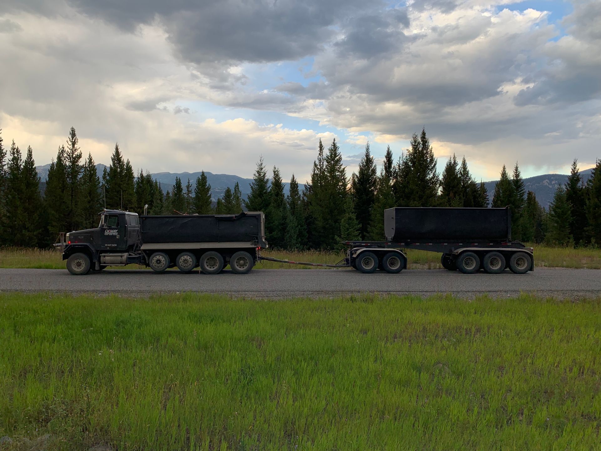 Two dump trucks are parked on the side of the road.