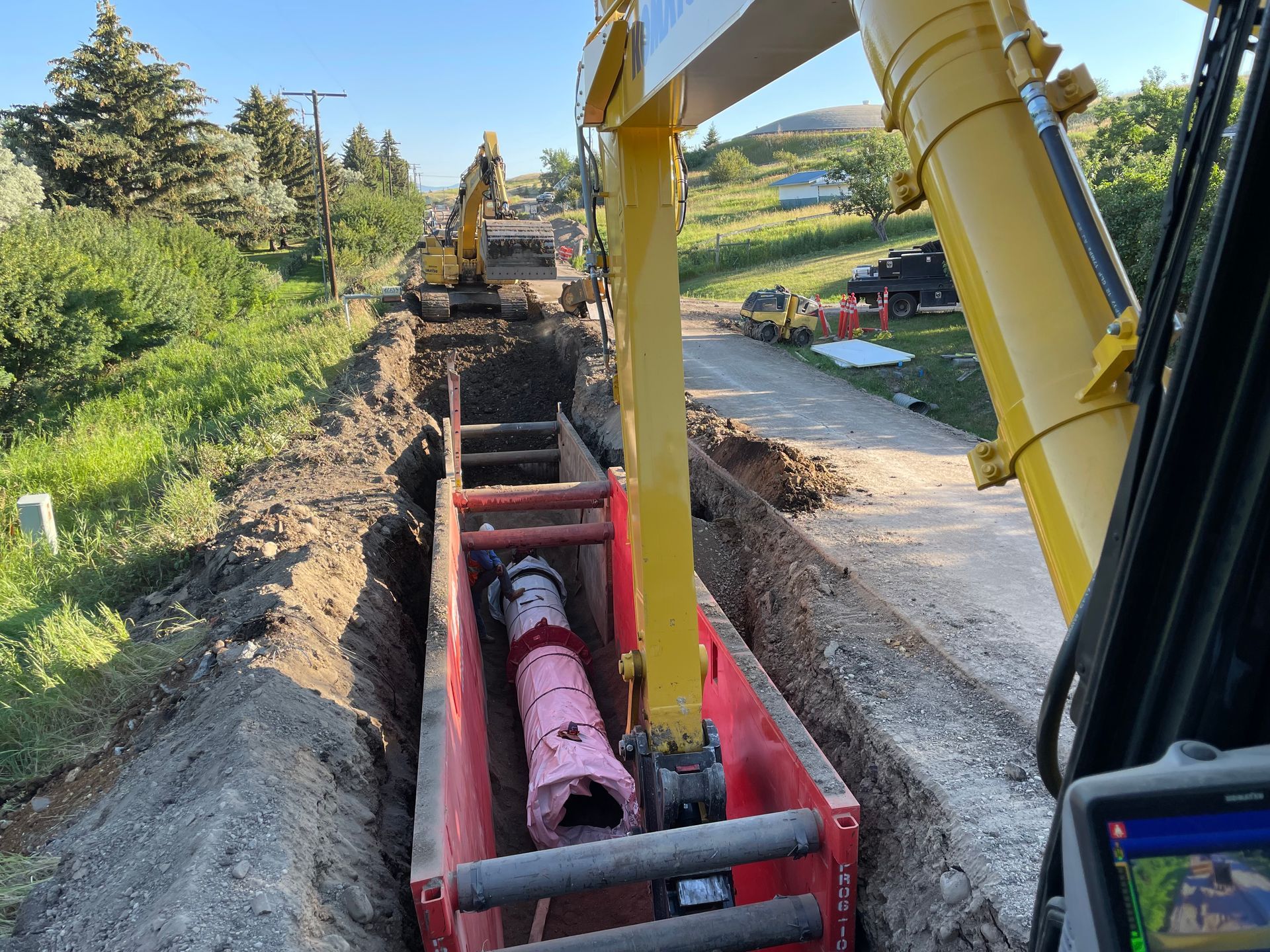 A yellow excavator is digging a hole for a pipe.