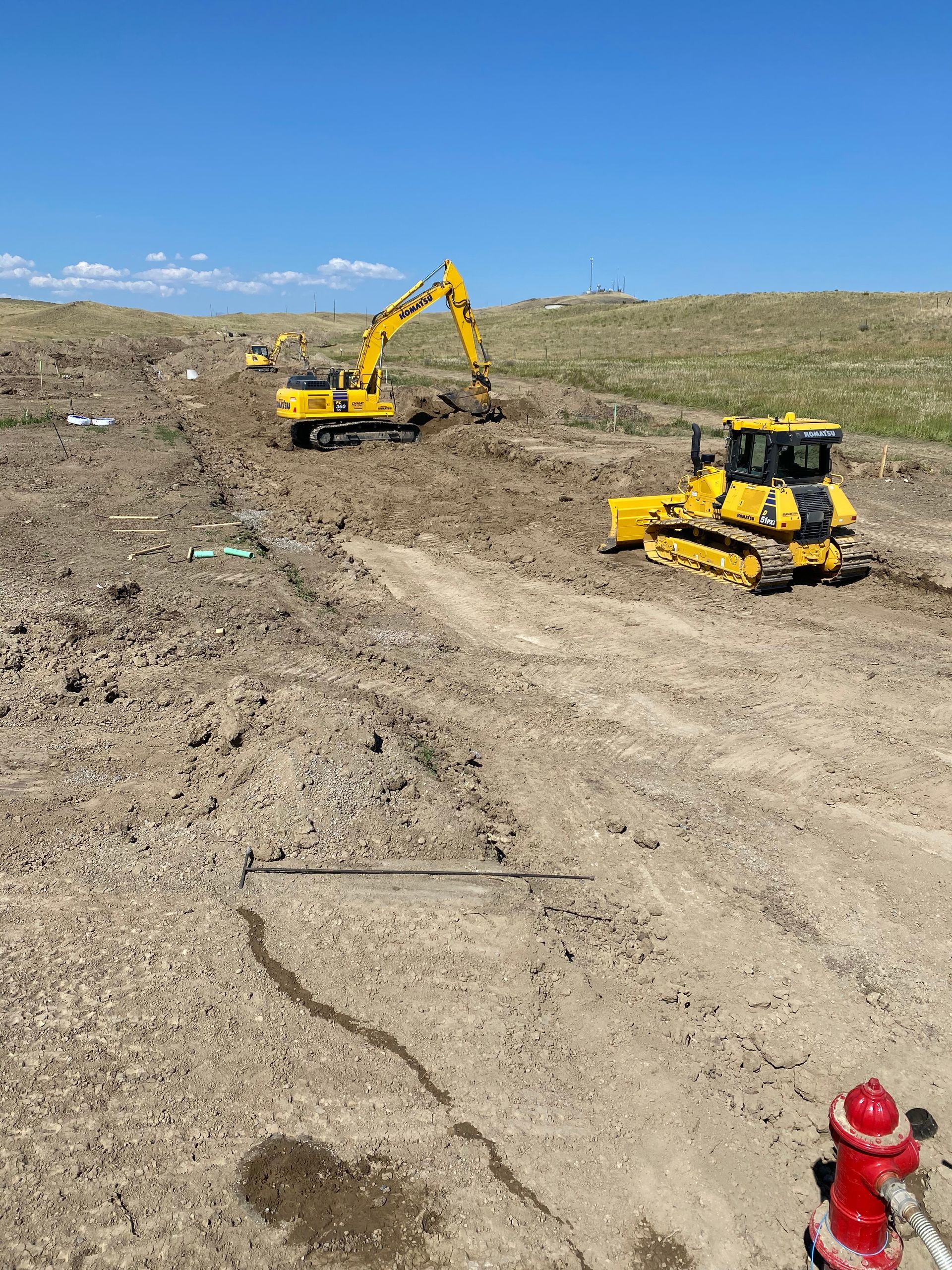 A bulldozer and an excavator are working on a dirt road.
