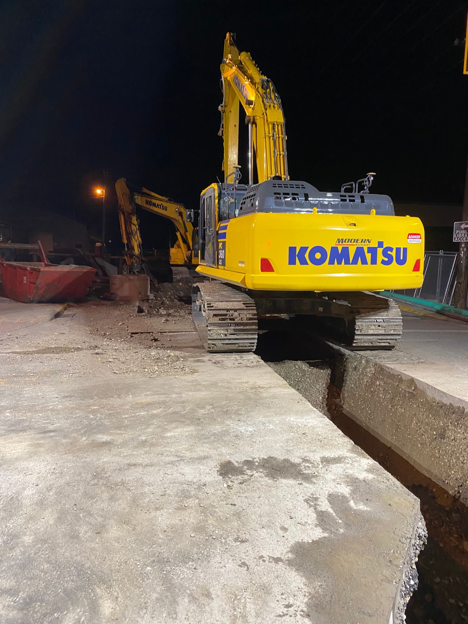 A yellow komatsu excavator is parked on the side of the road