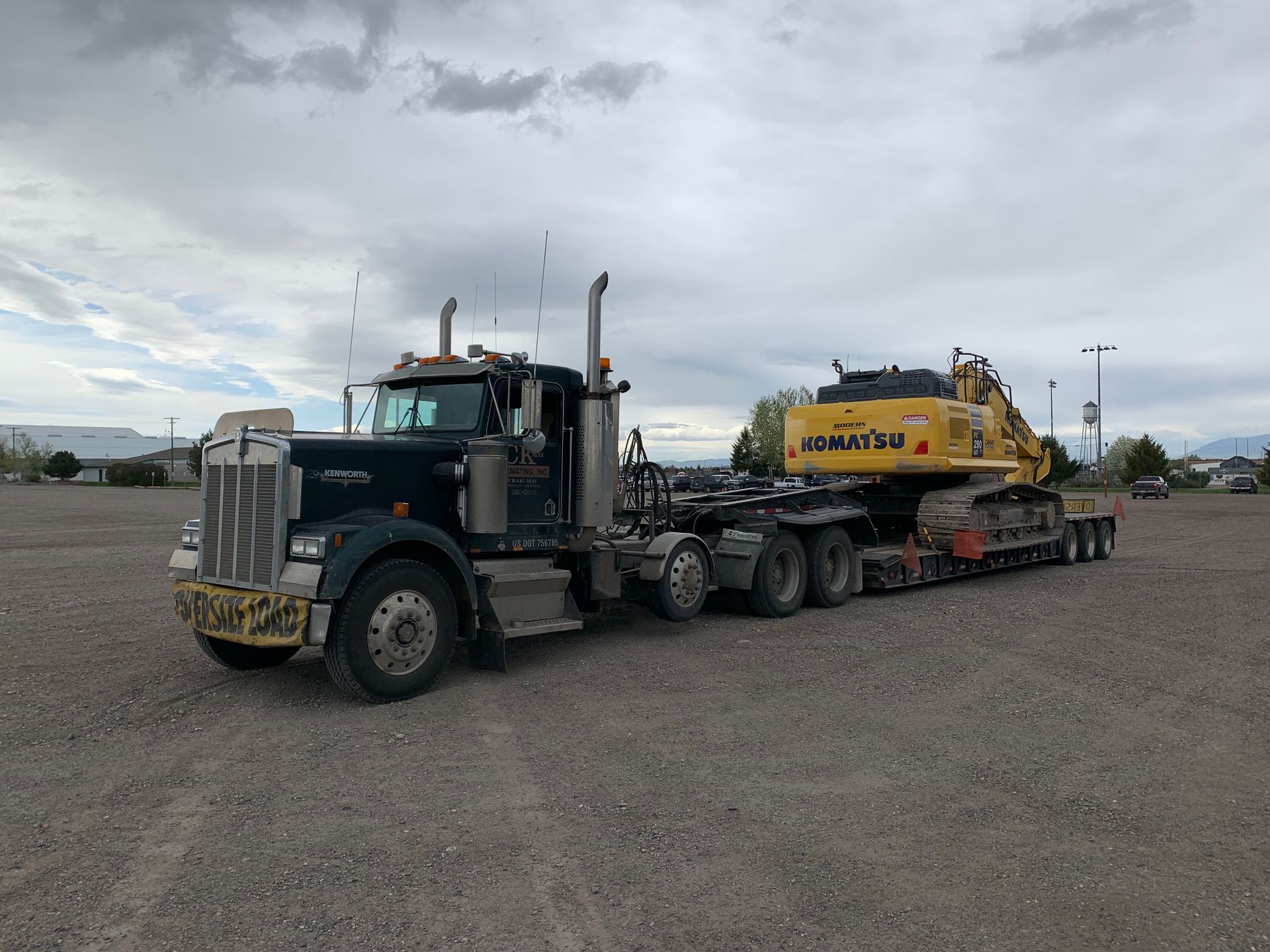 A semi truck is carrying a yellow excavator on a trailer.