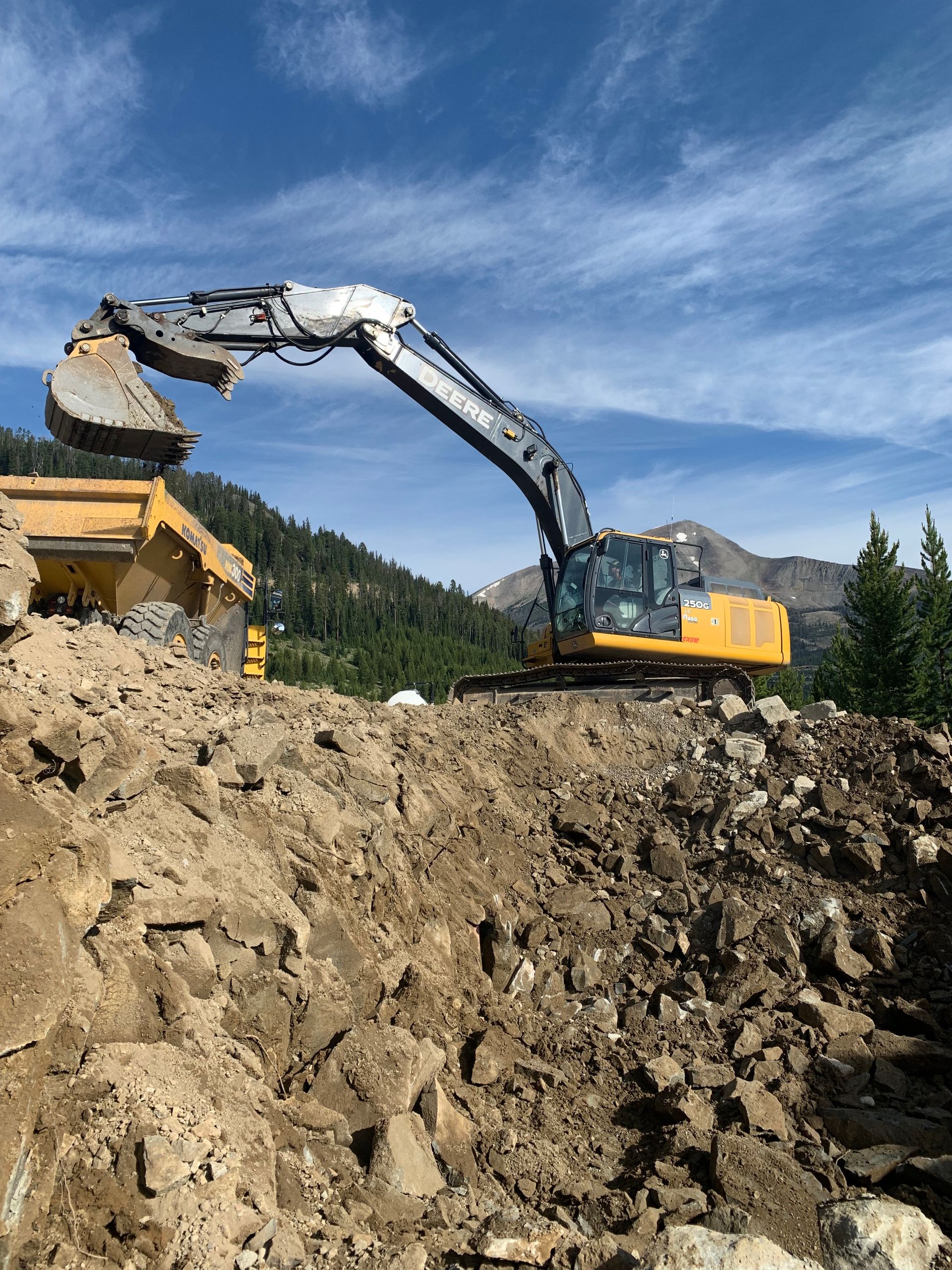 A large yellow excavator is digging a pile of dirt.