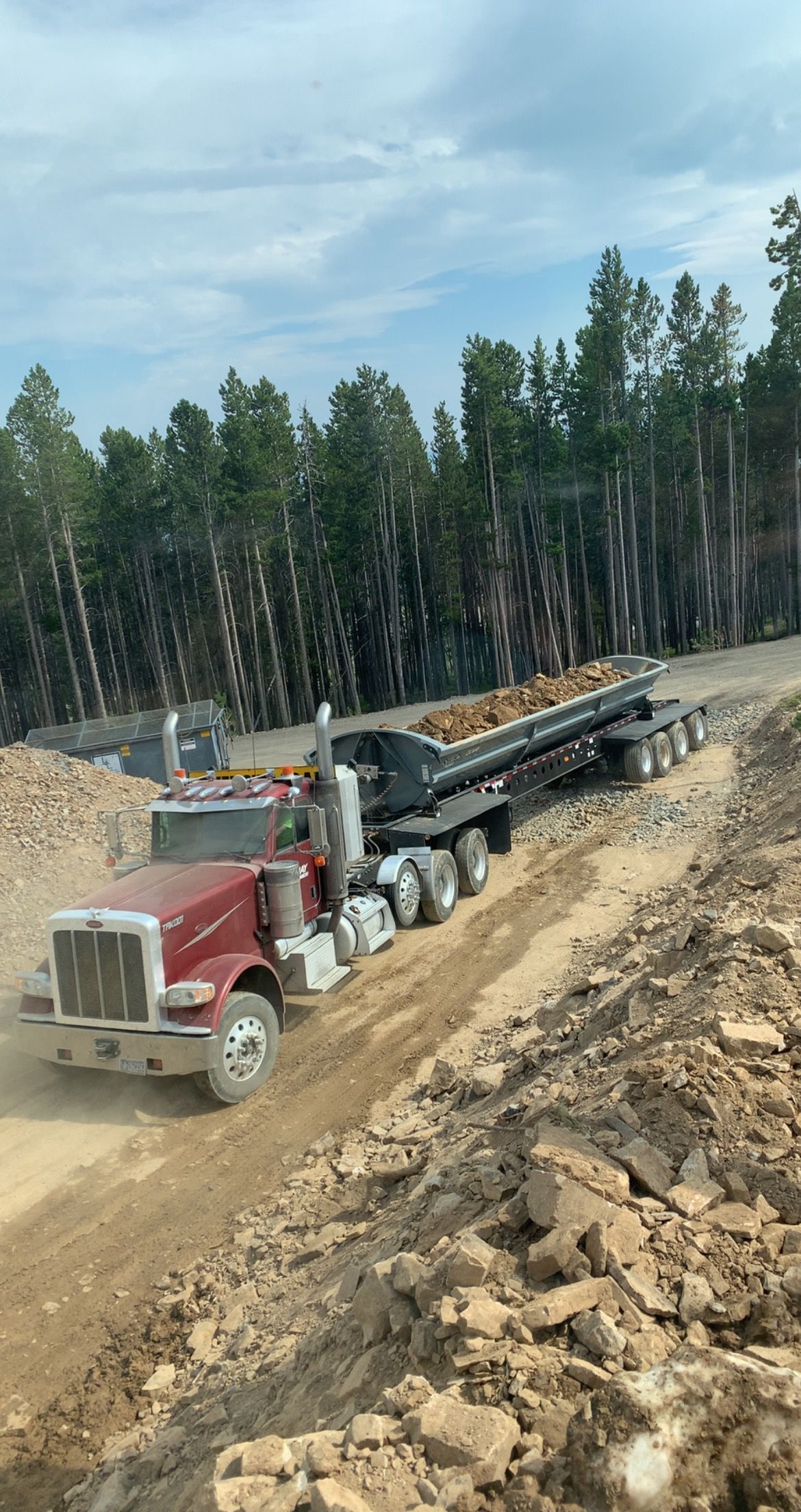 A semi truck is driving down a dirt road.