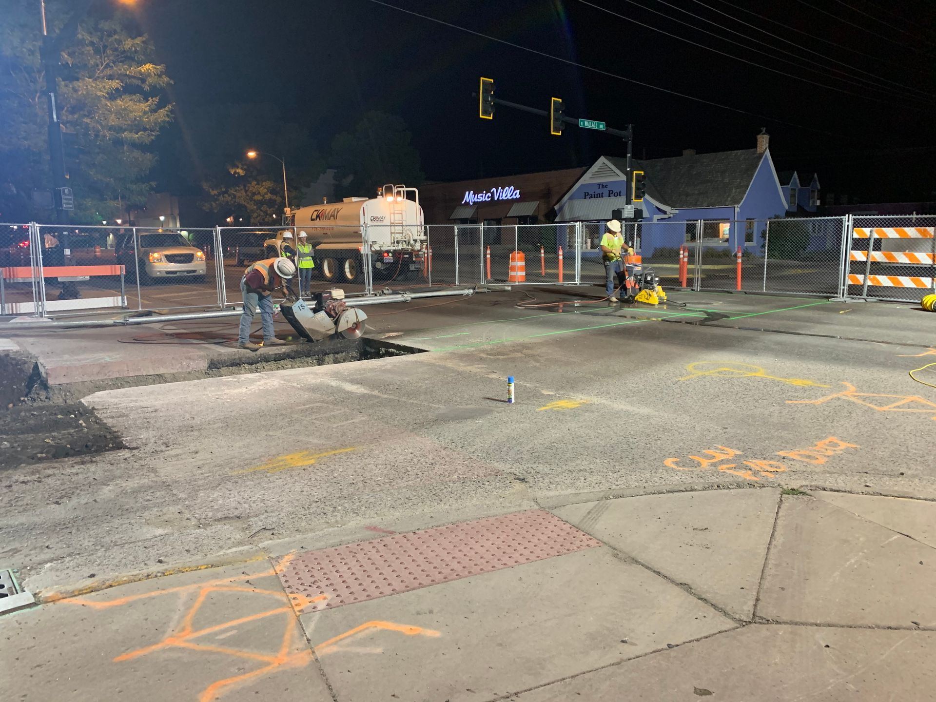 A group of construction workers are working on a street at night.