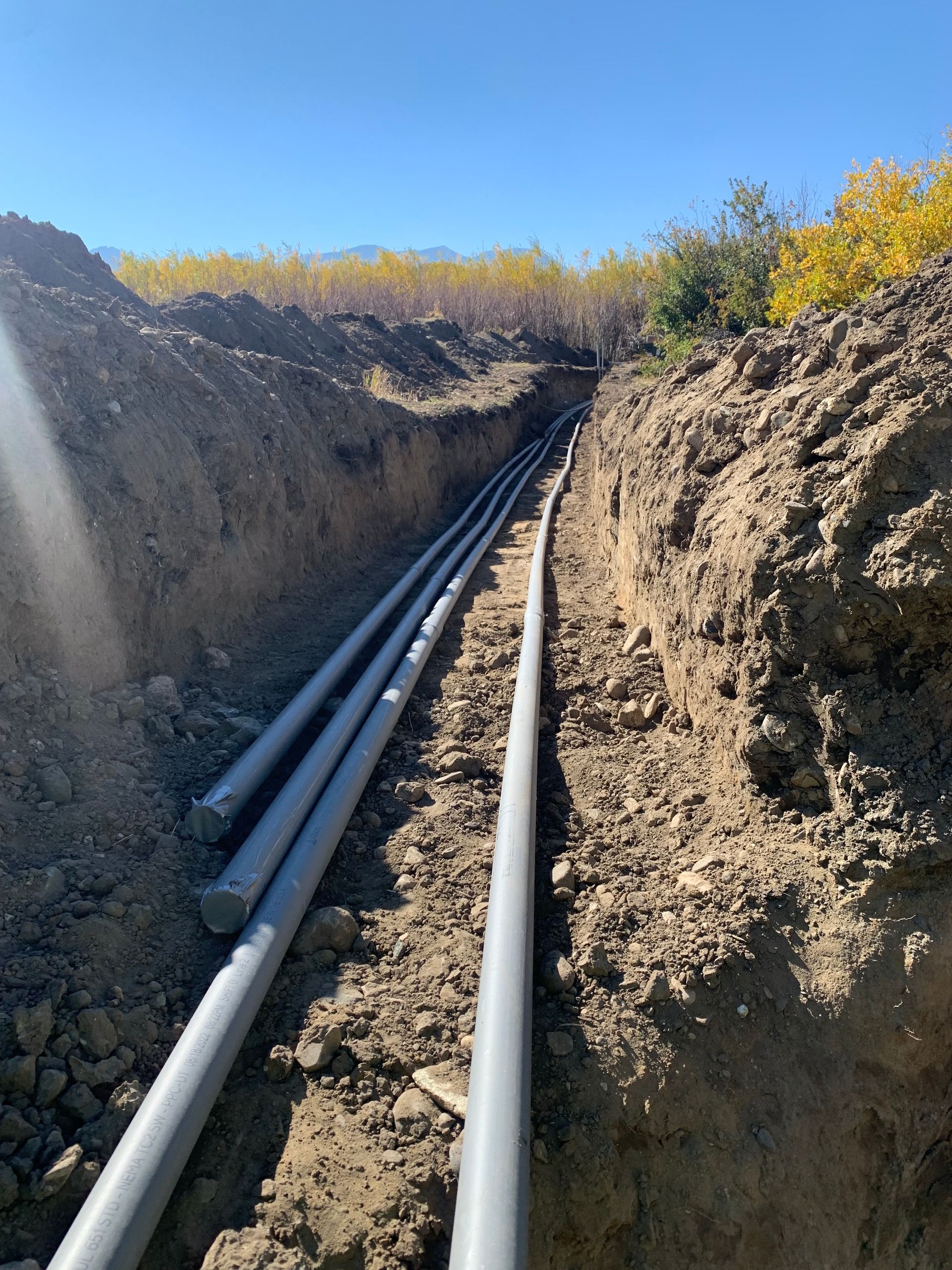 A bunch of pipes are laying in the dirt
