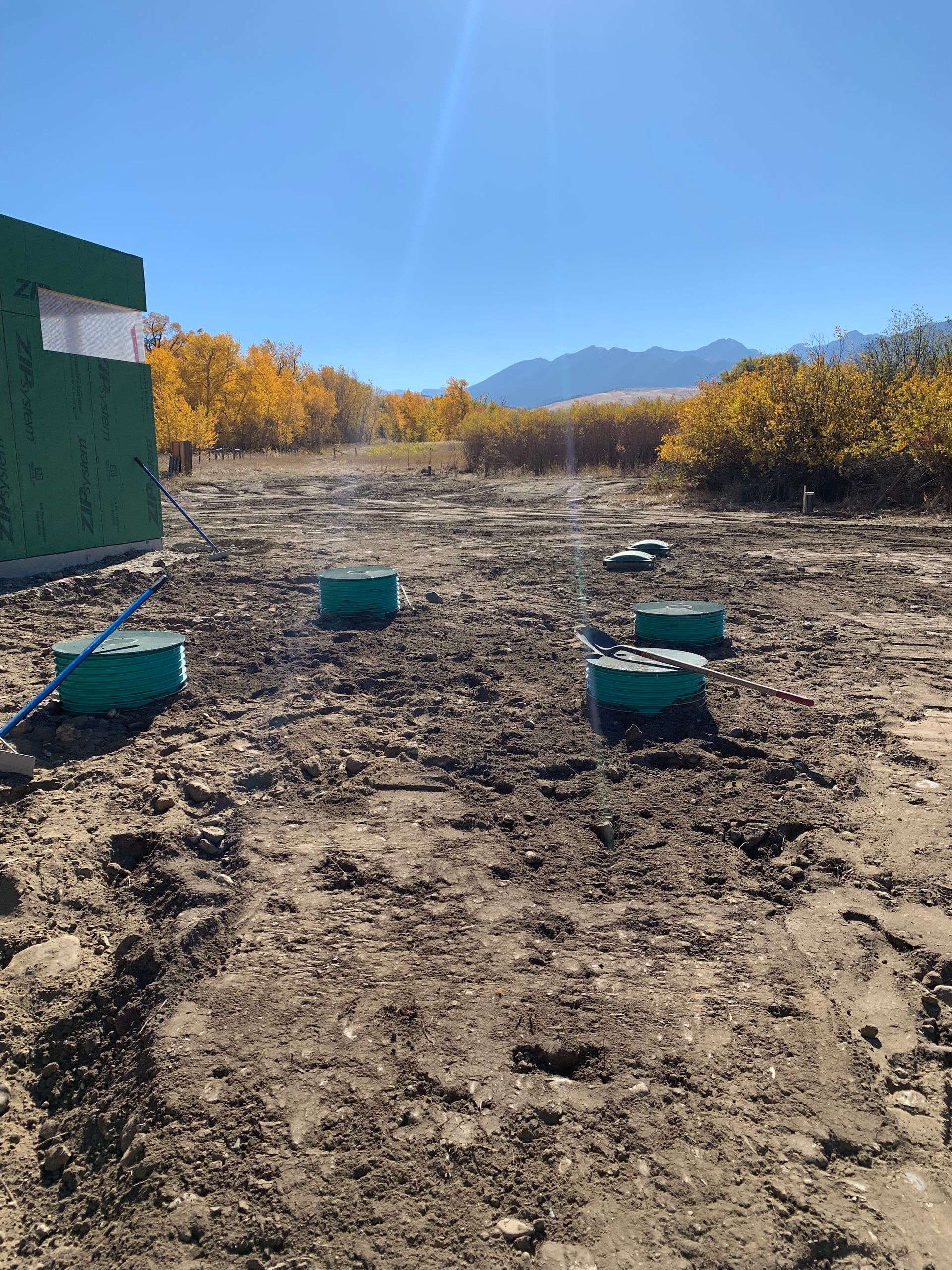 A dirt field with a green building in the background.