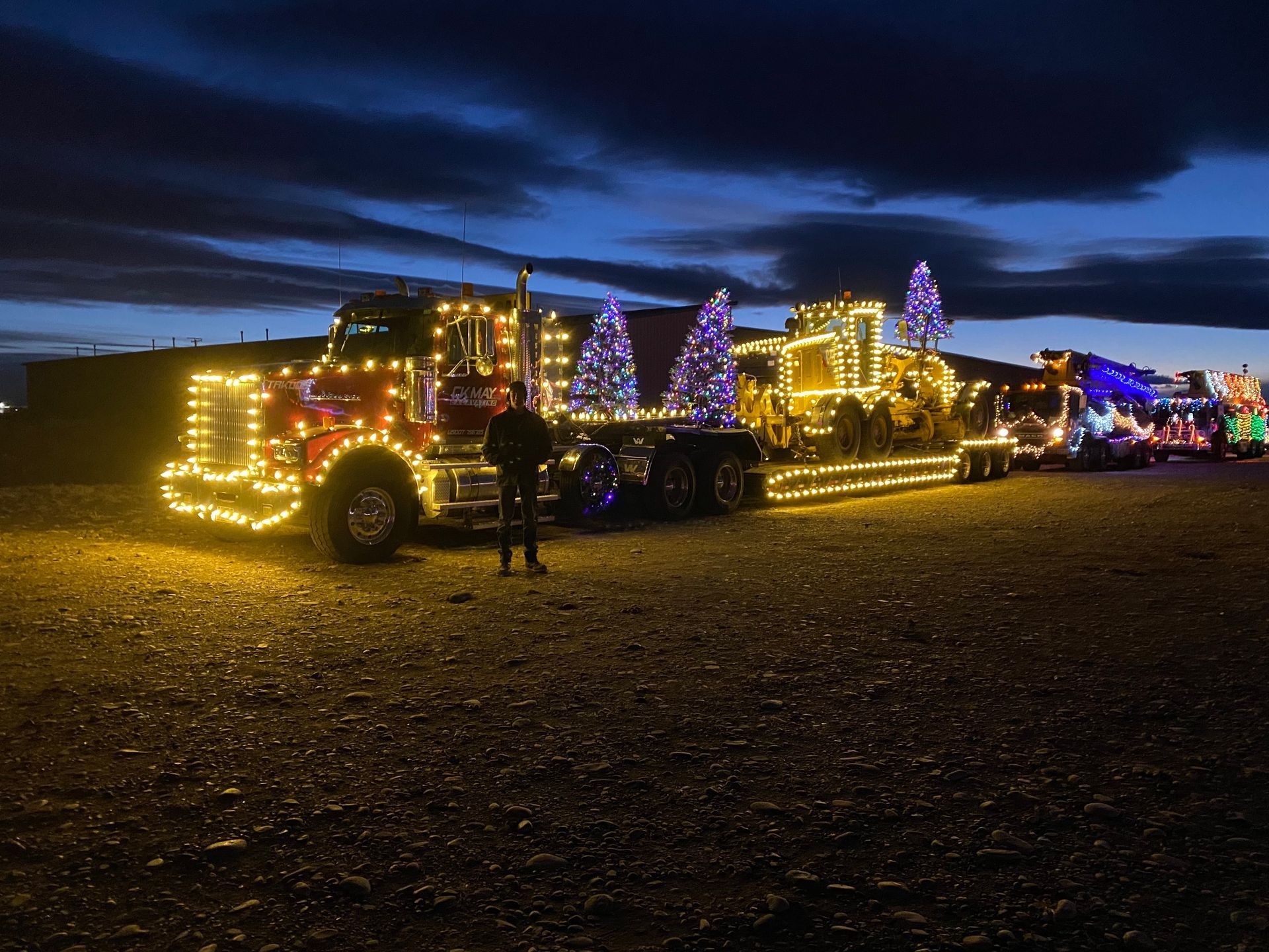 A man is standing in front of a truck decorated with christmas lights.