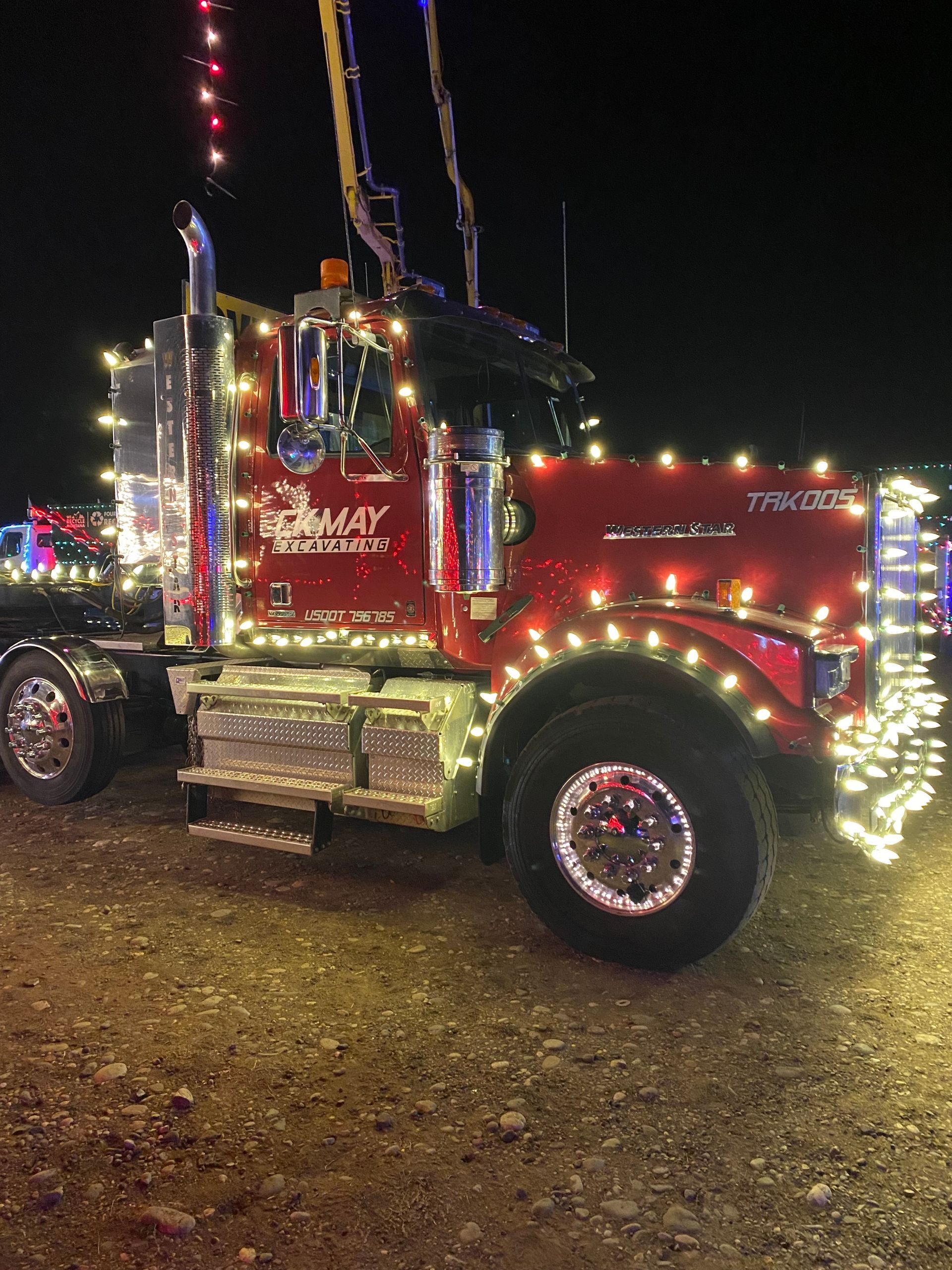 A red semi truck is decorated with christmas lights.