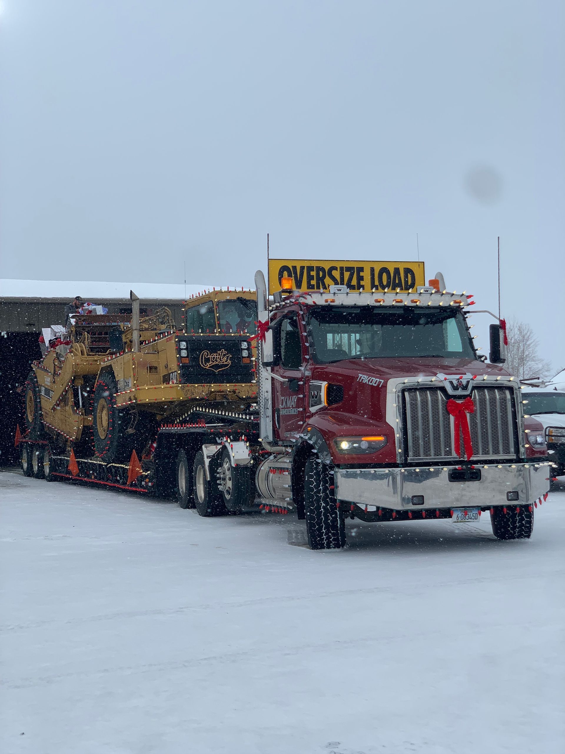 A semi truck is carrying a bulldozer in the snow.