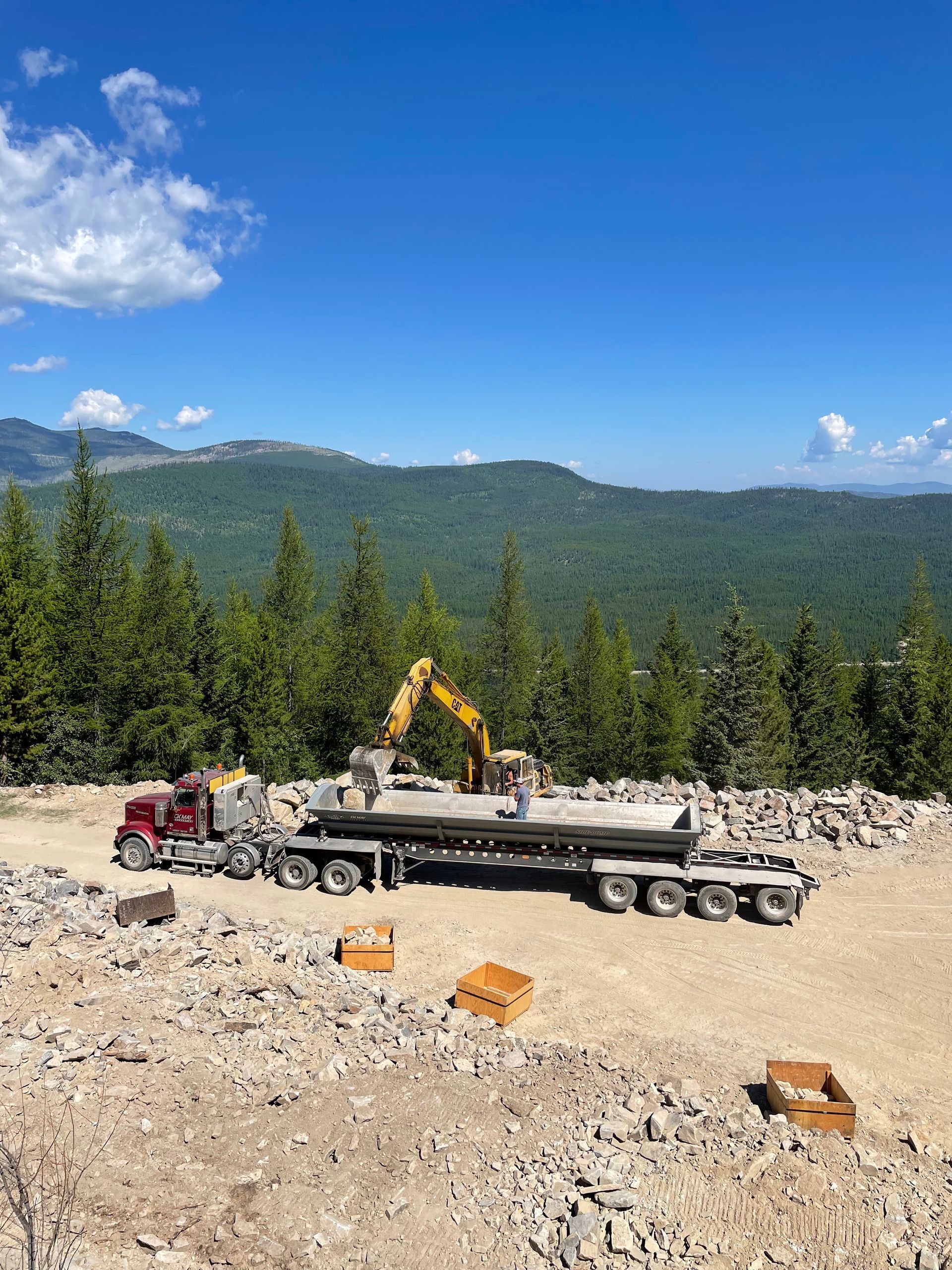 A truck is driving down a dirt road with mountains in the background.