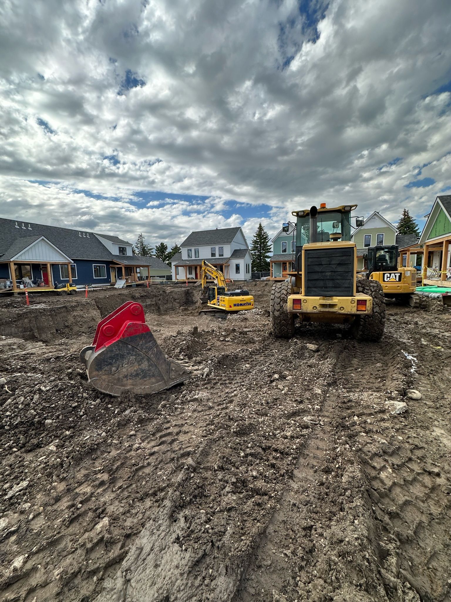 A group of construction vehicles are driving through a dirt field.