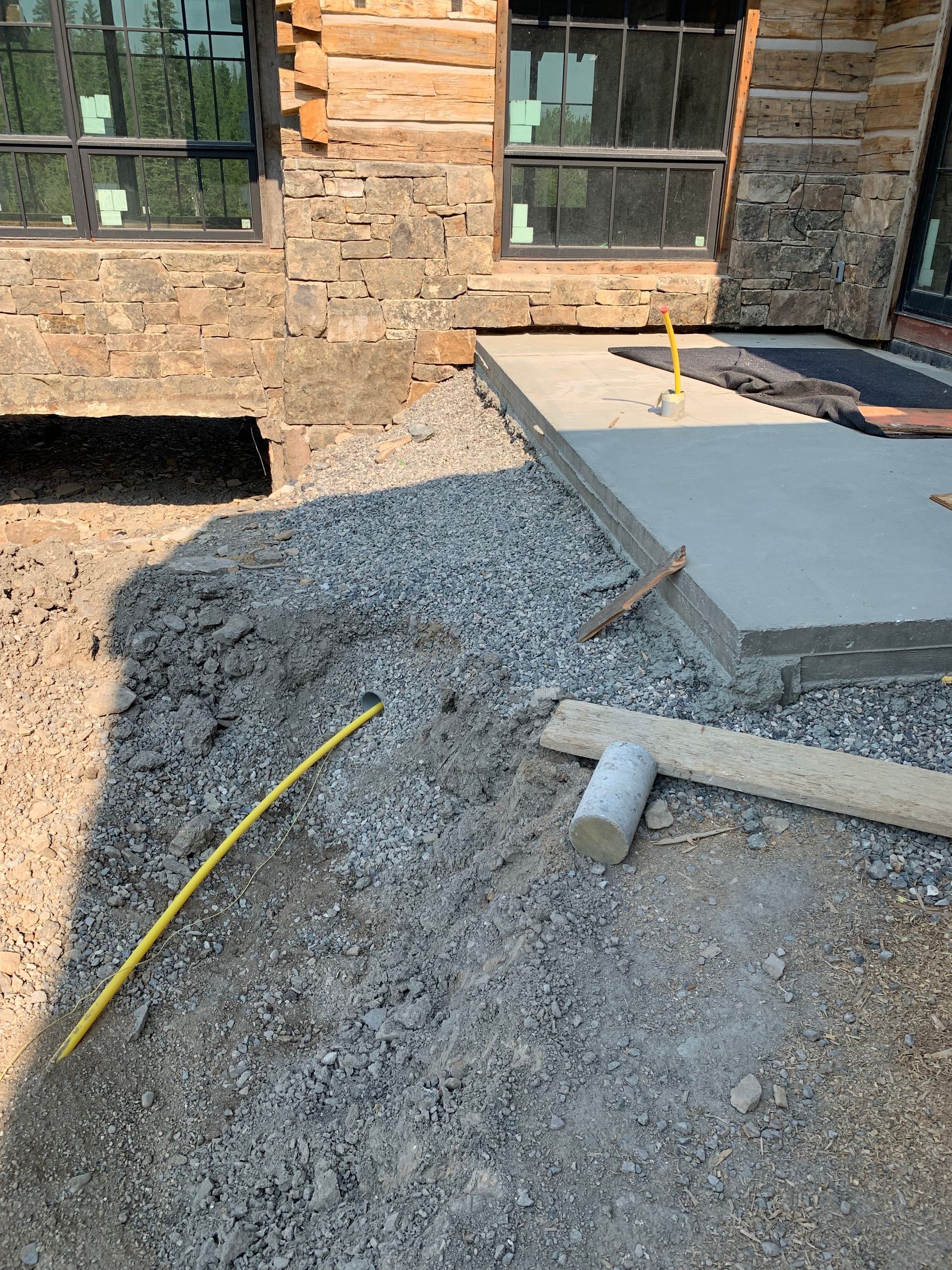 A concrete walkway is being built in front of a log cabin.