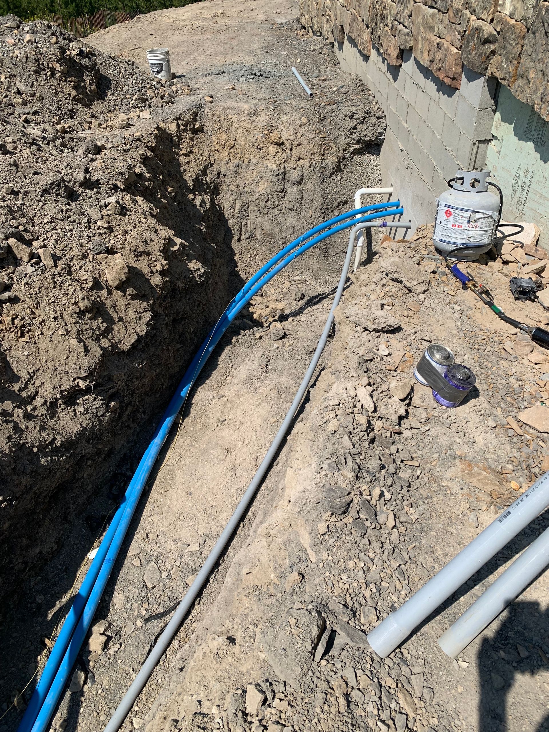 A bunch of blue pipes are laying in the dirt