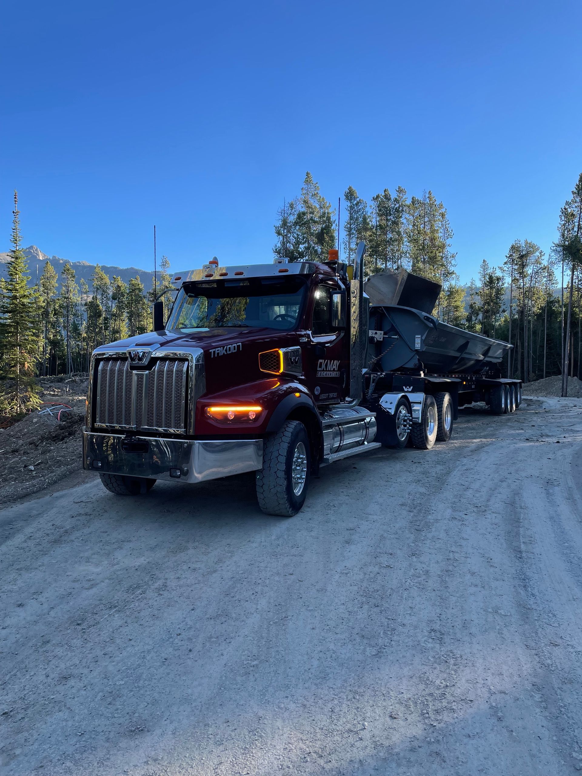 A semi truck is driving down a dirt road.