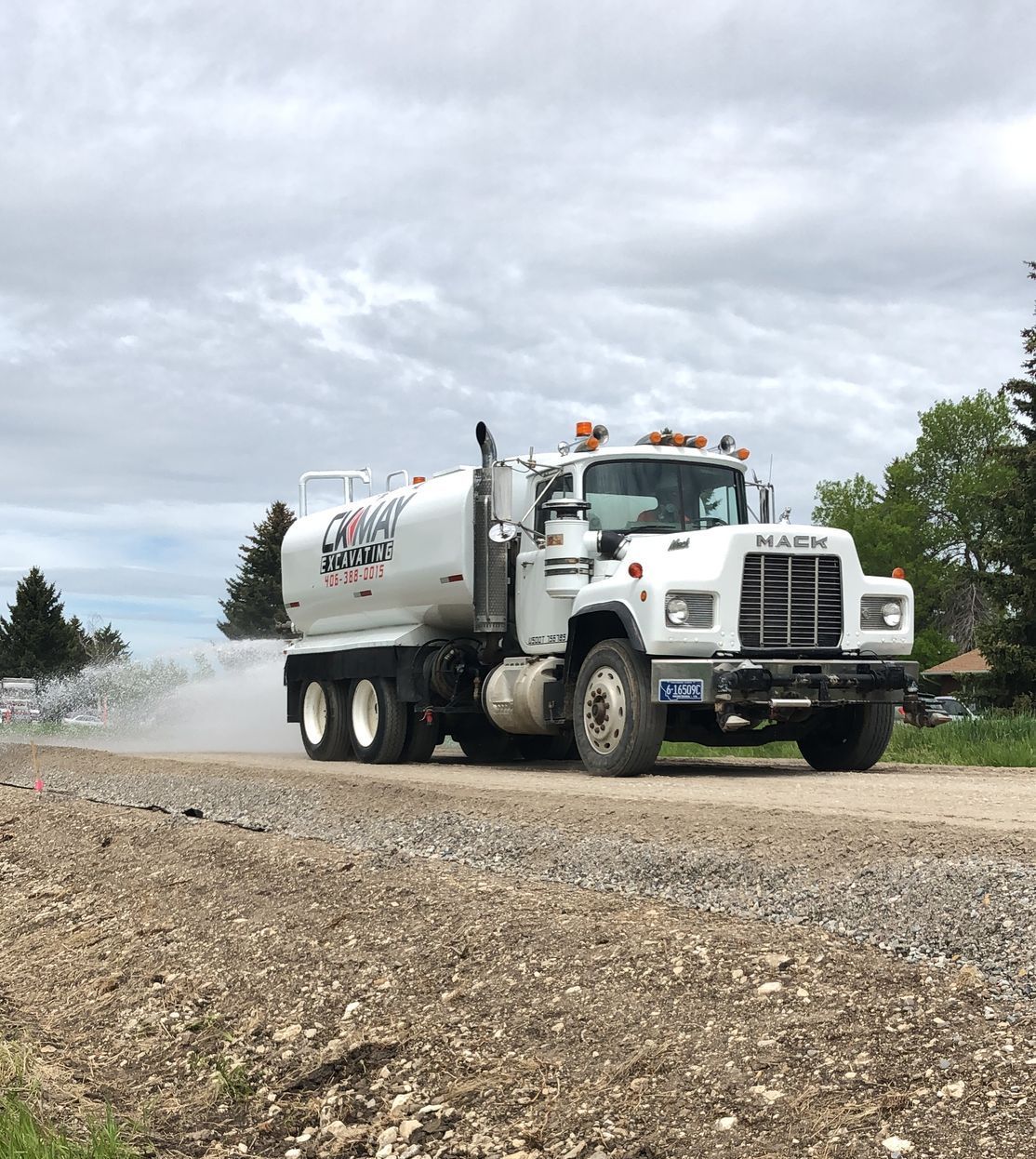 A white truck is driving down a gravel road.
