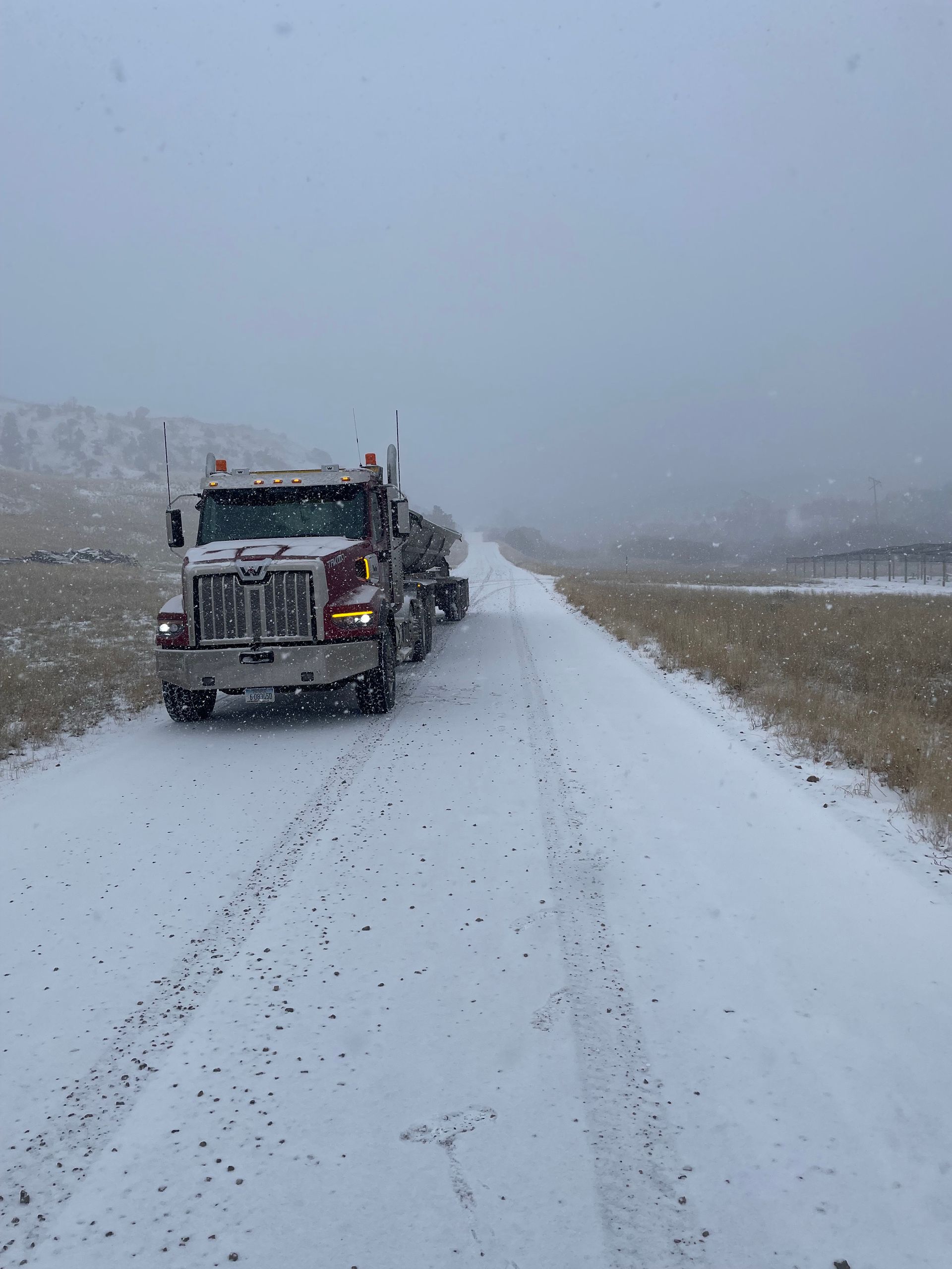 A semi truck is driving down a snowy road.