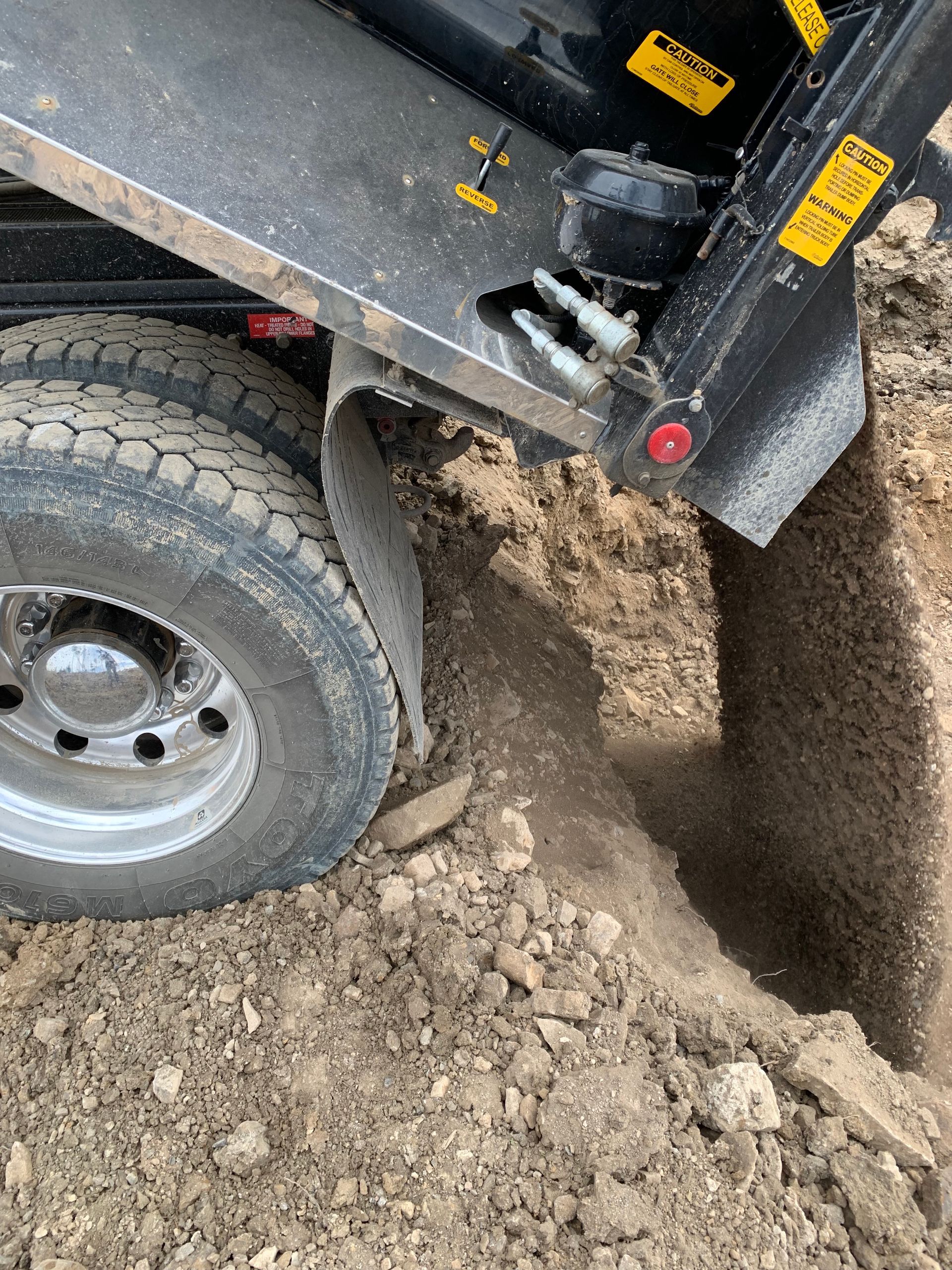 A dump truck is digging a hole in the dirt.