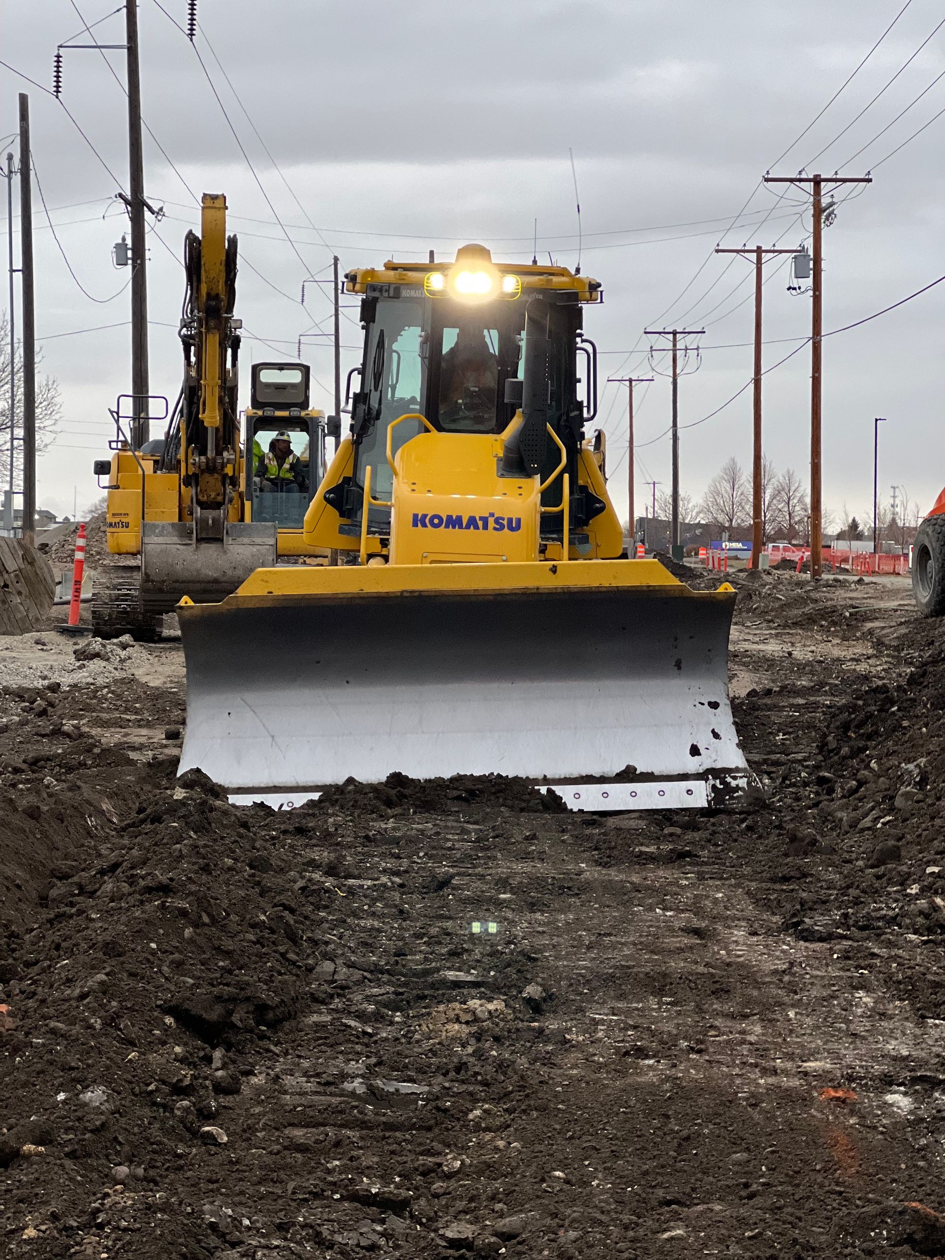 A yellow komatsu bulldozer is driving through a dirt field