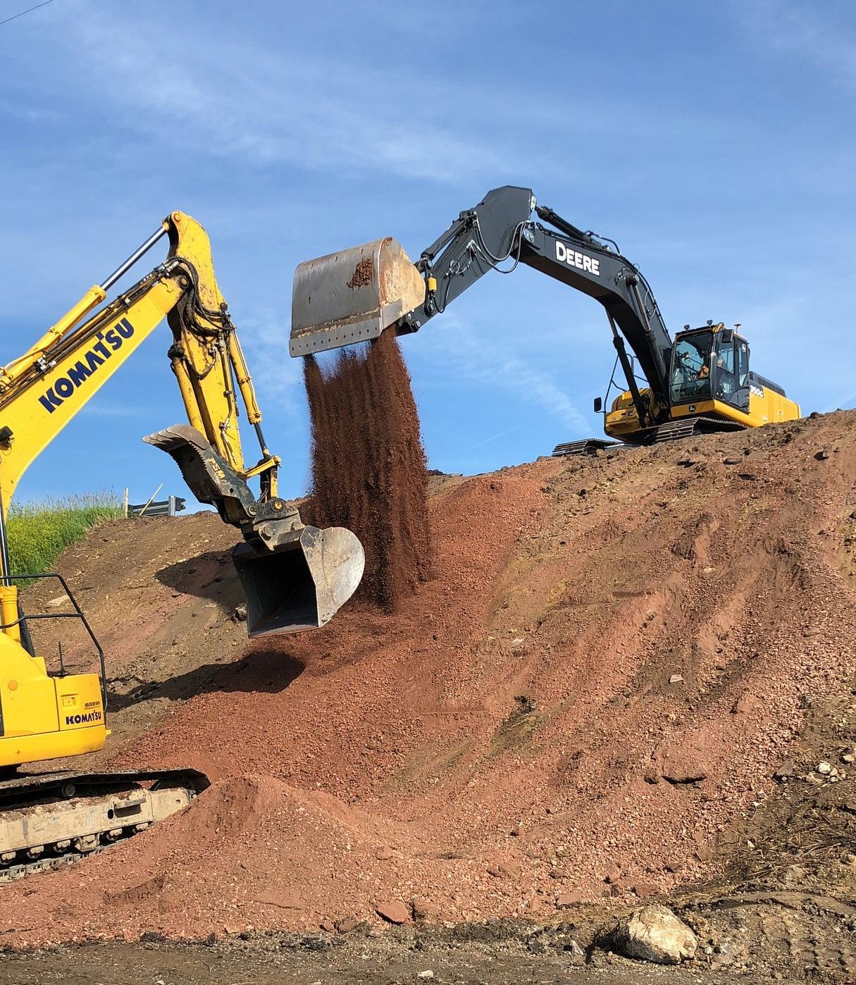 A komatsu excavator is pouring dirt into a pile.