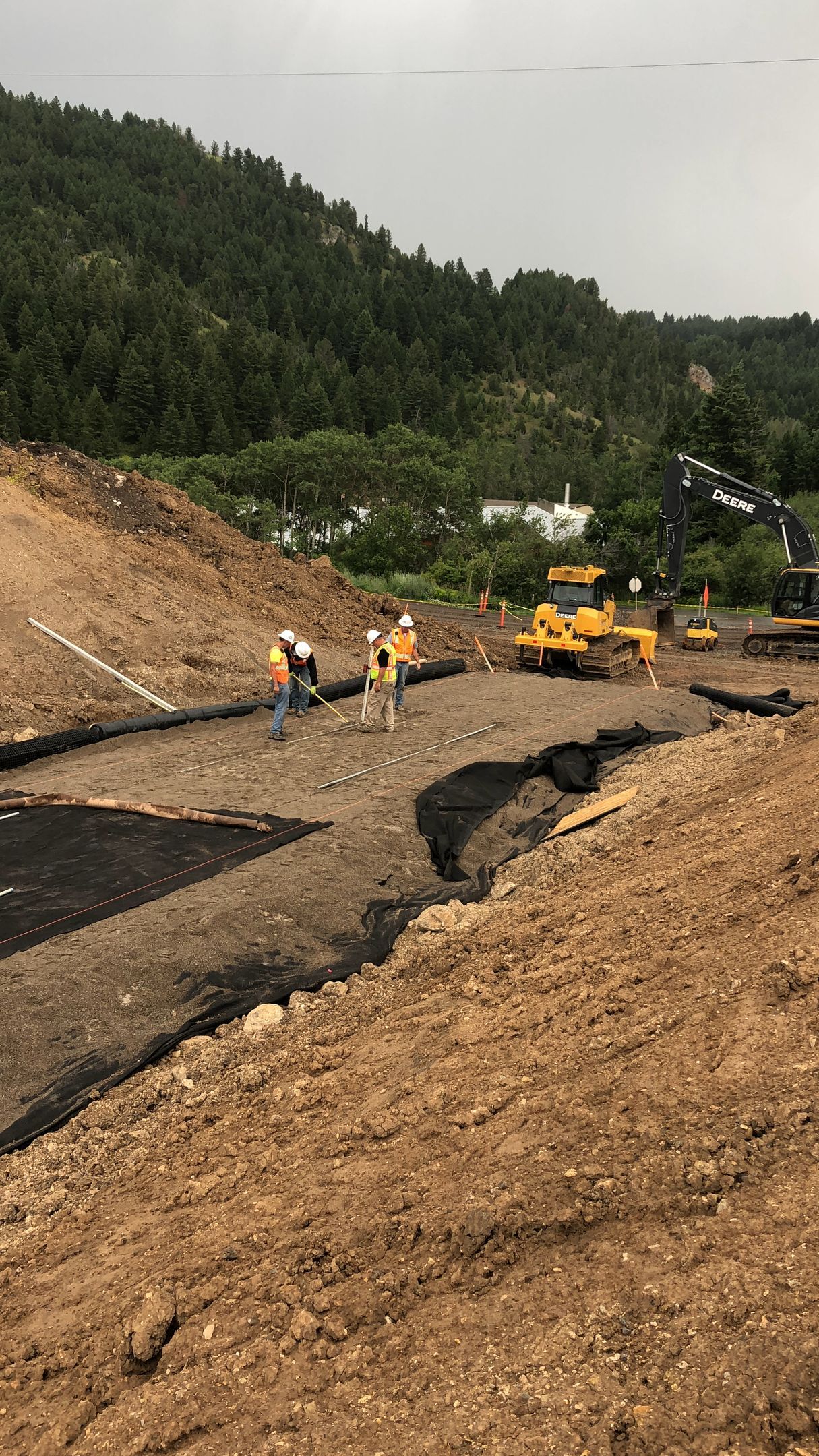 A group of construction workers are working on a dirt hill.
