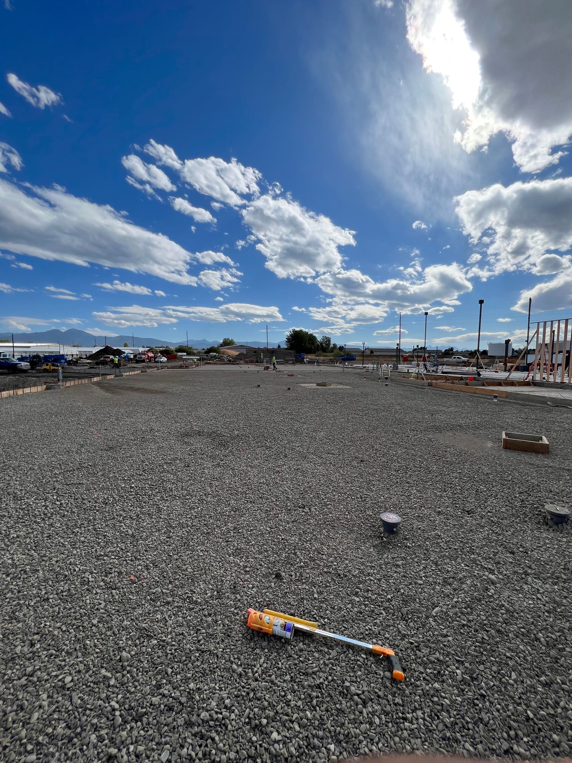 A baseball bat is laying on the ground in a gravel field.