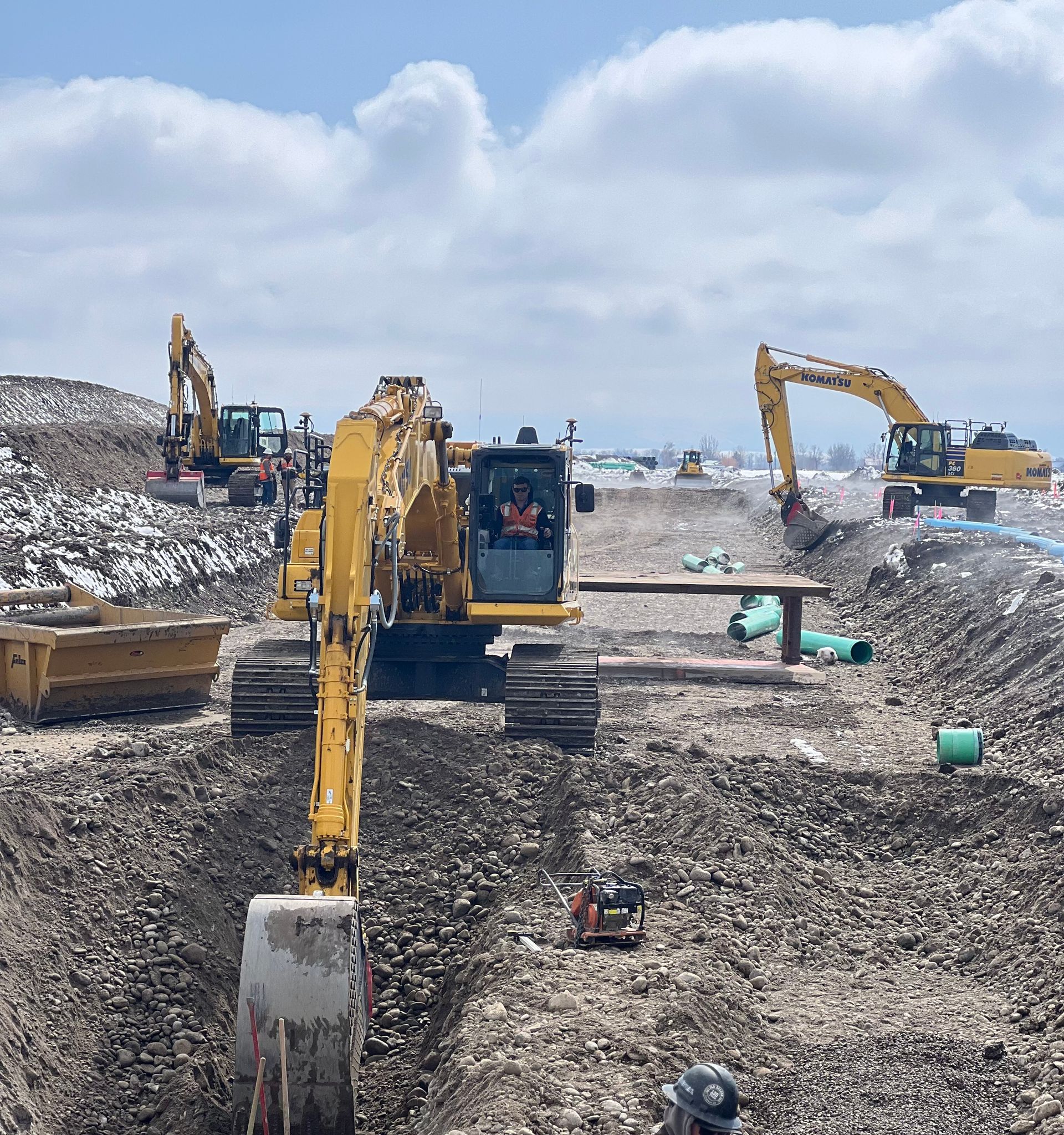 A yellow excavator is digging a hole in the dirt