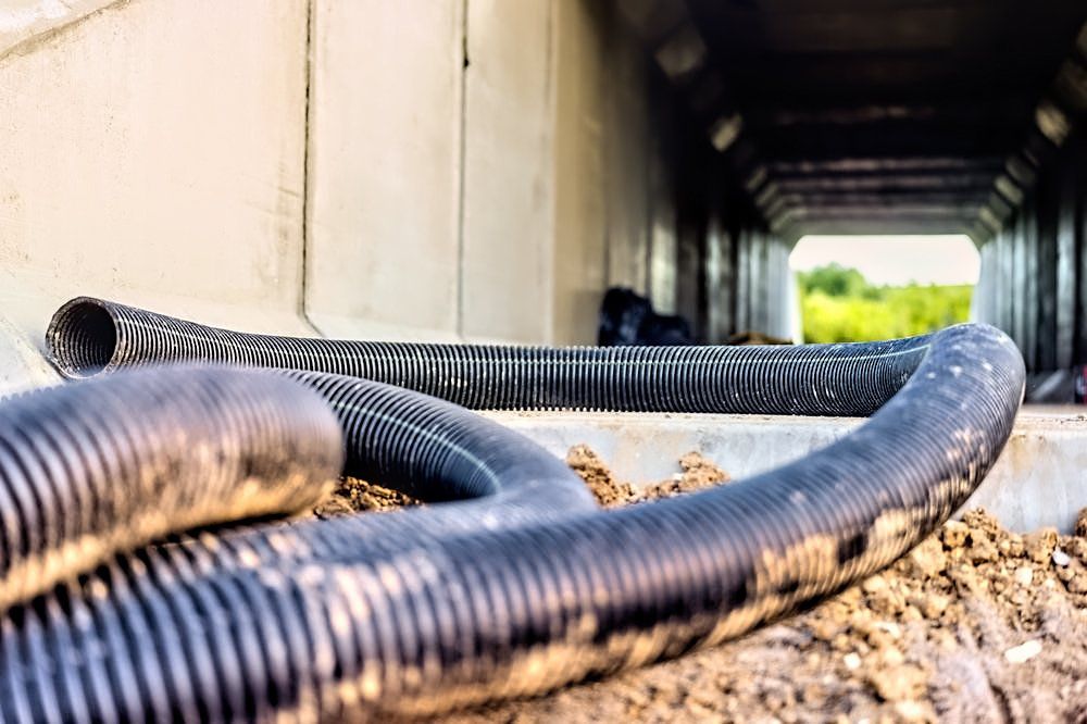 A bunch of hose laying on the ground next to a tunnel.