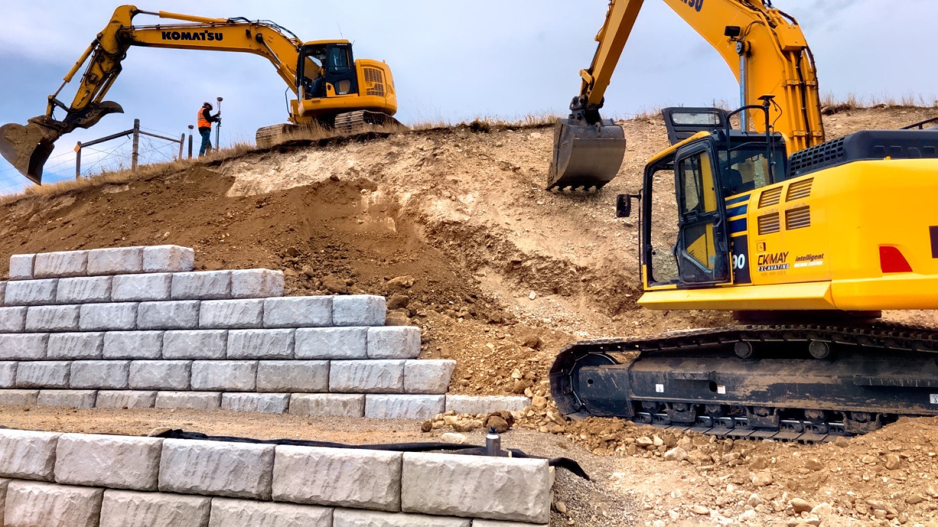 Two yellow excavators are working on a construction site.