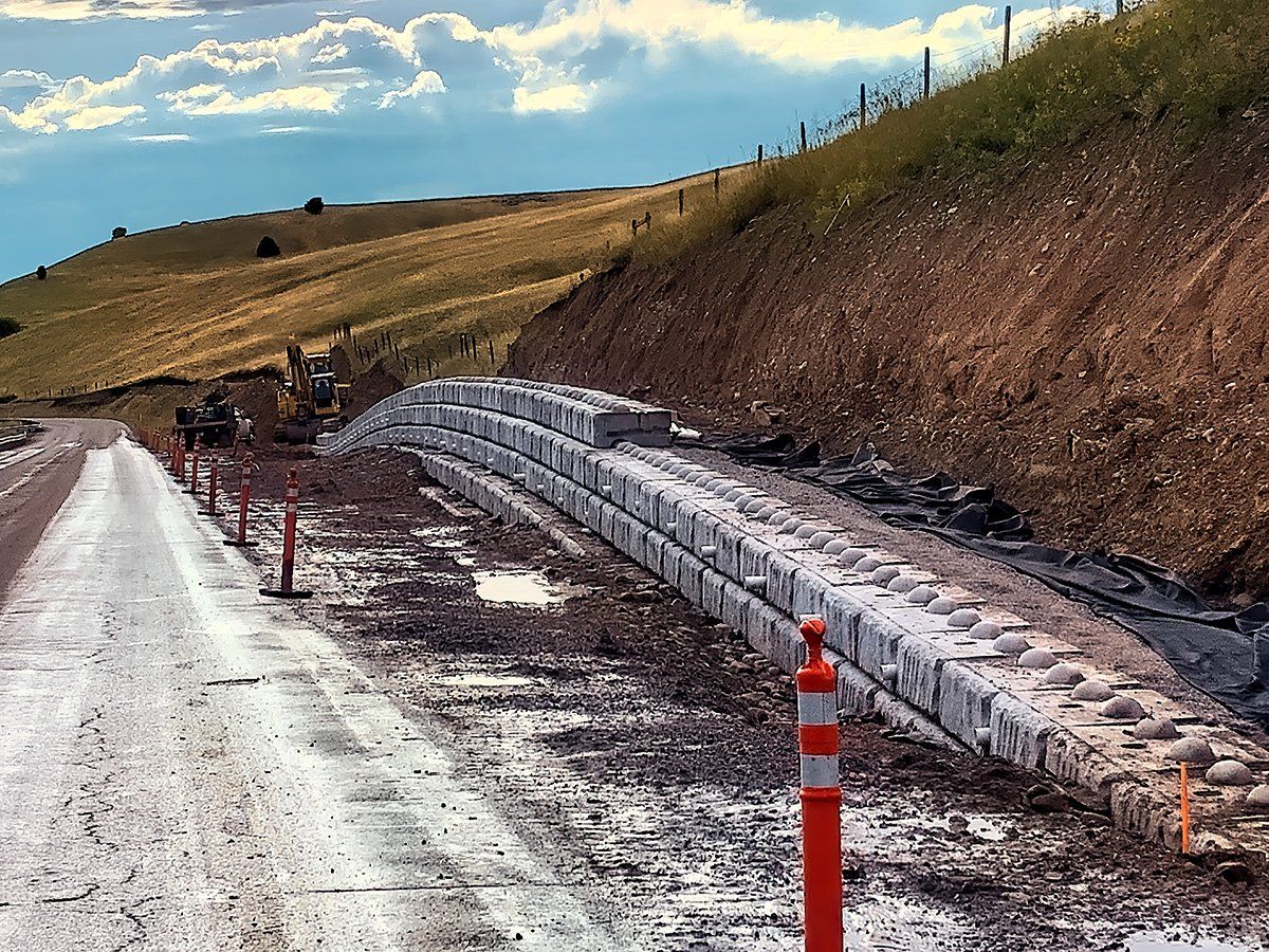 A dirt road with a concrete wall on the side of it