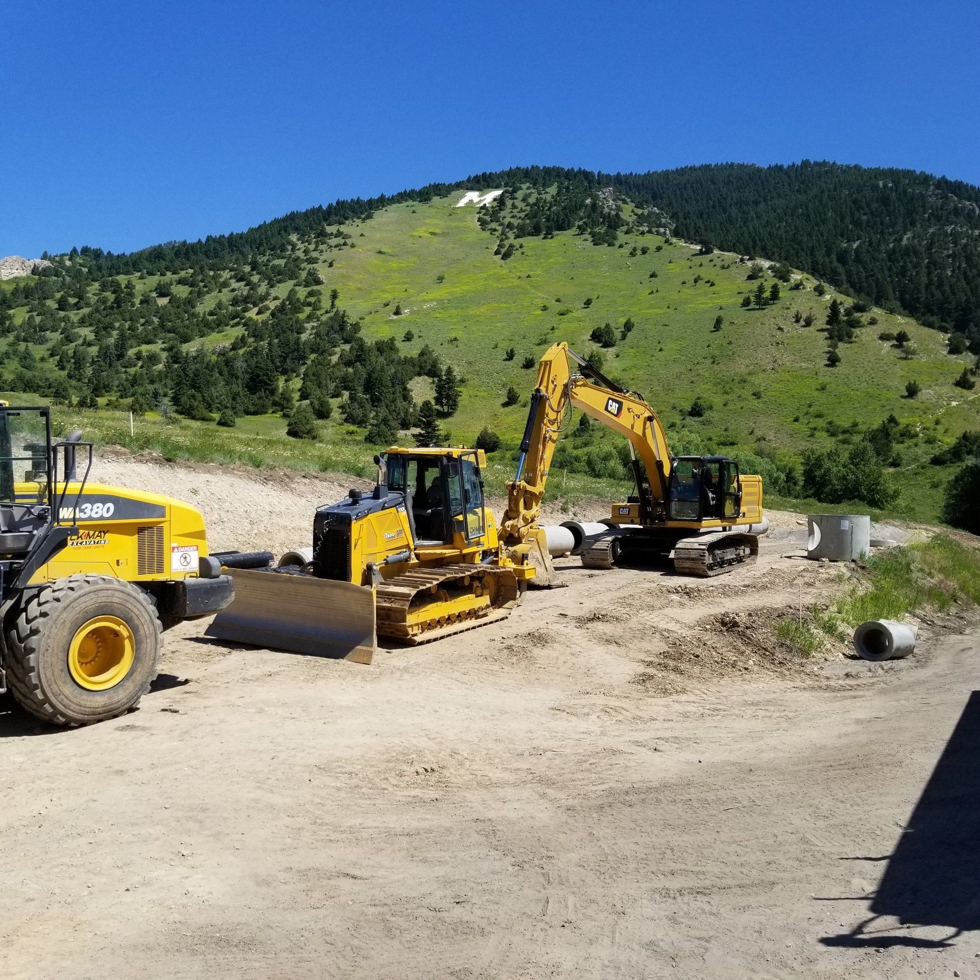 A bulldozer and an excavator are parked in a dirt field